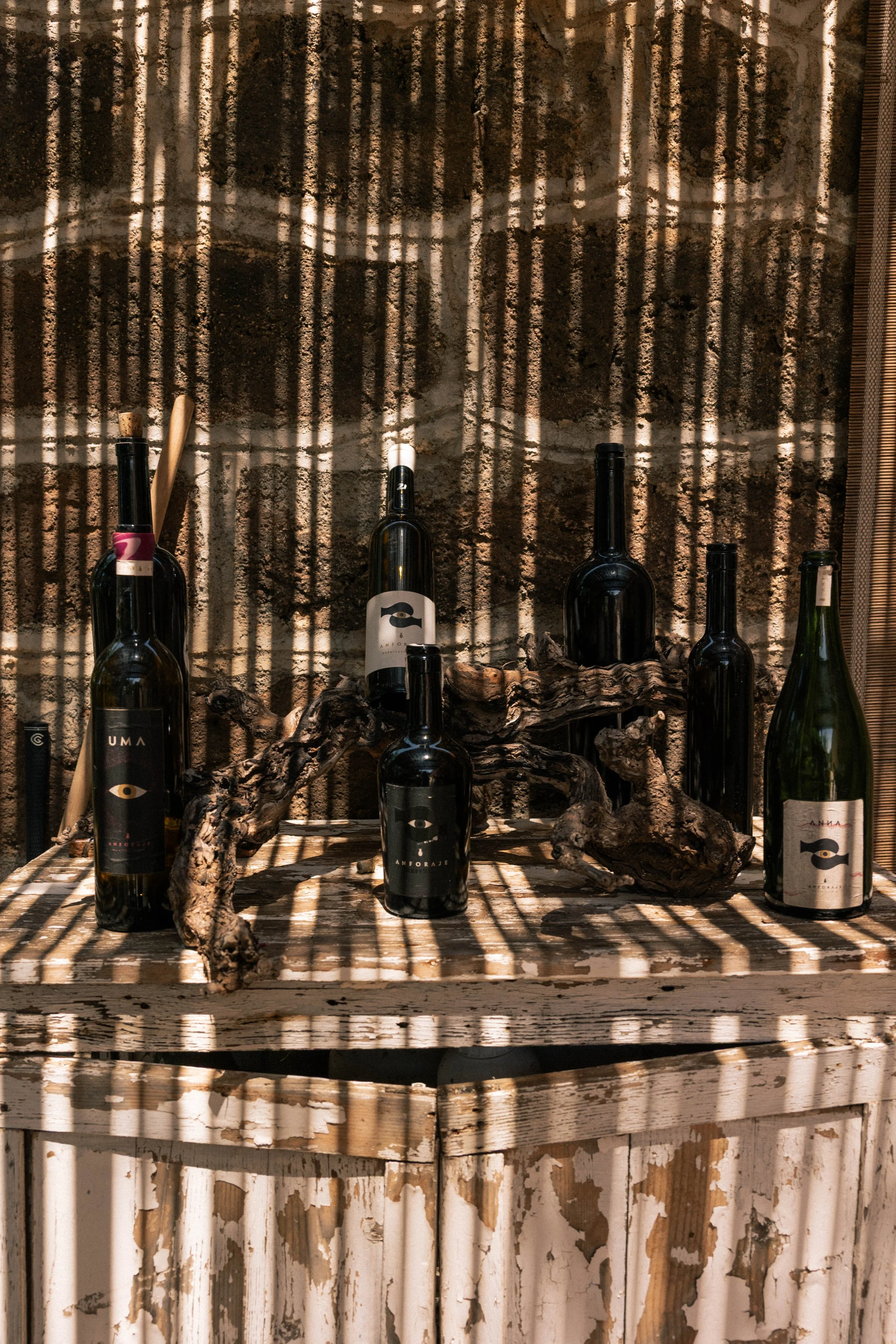 casting striped shadows on Anforaje wine bottles 