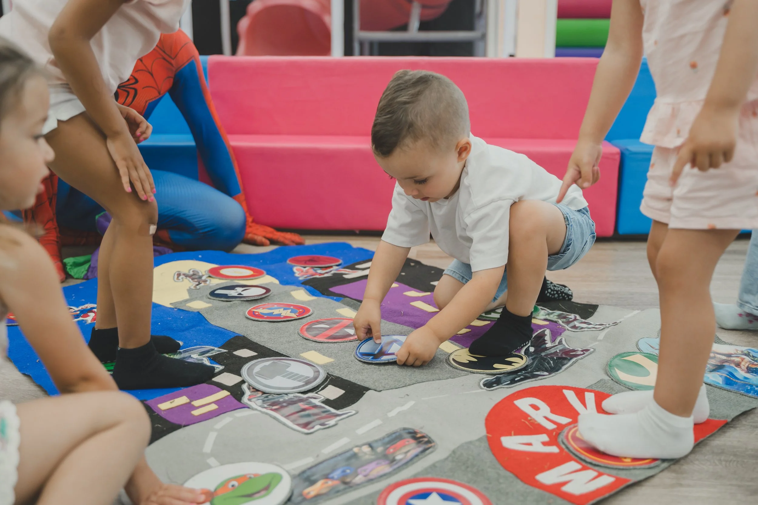Children playing a board game on the floor with colorful game pieces and character tokens.