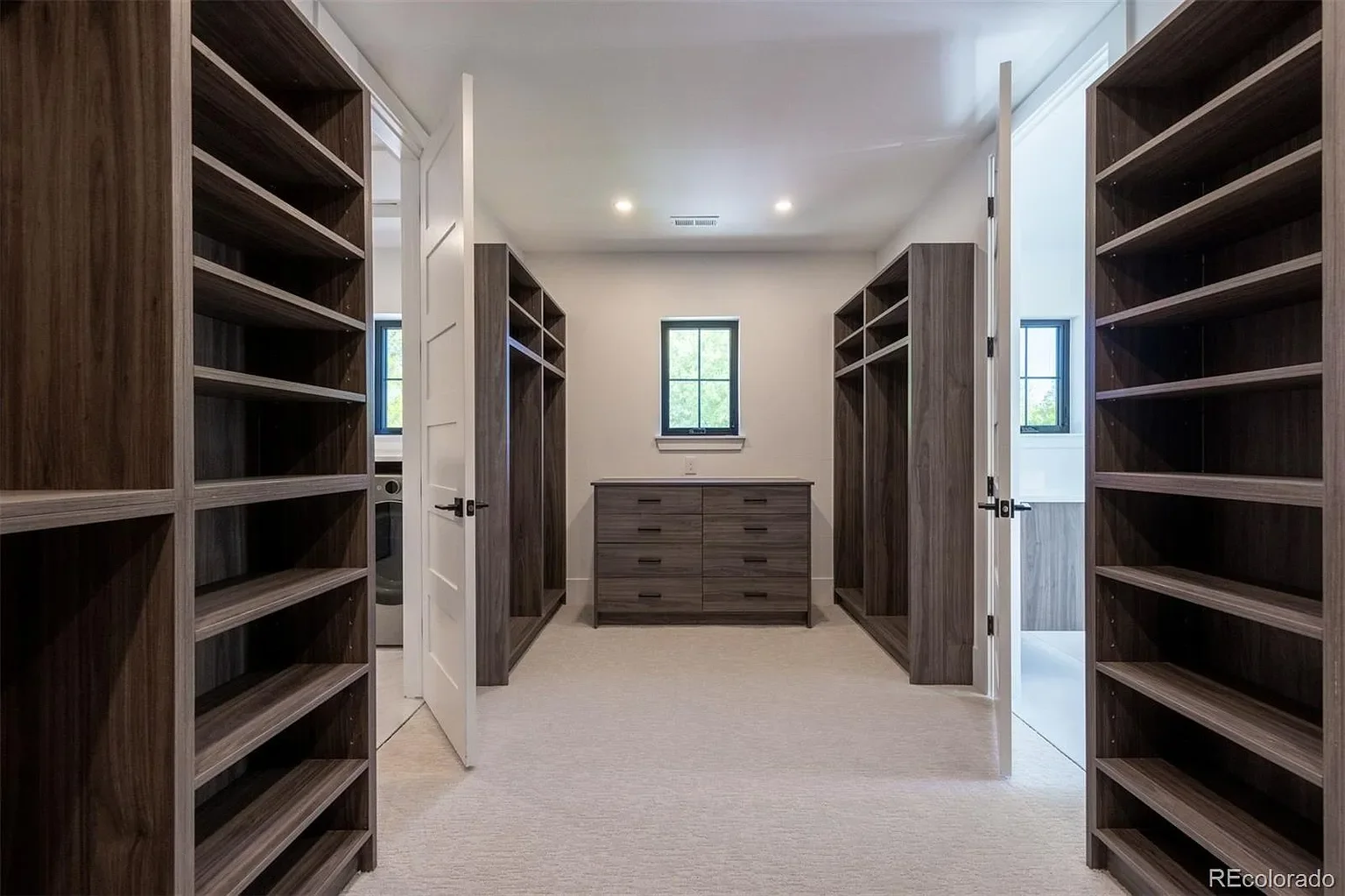 Spacious primary walk-in closet with custom wood built-ins and center dresser island at 2200 Newton St in Sloan's Lake, Denver, built by The Rukavina Companies