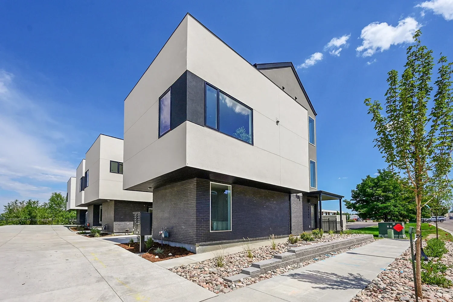 Modern duplex exterior at Gemini Townhomes in Wheat Ridge featuring dark brick base and white stucco upper level, built by The Rukavina Companies