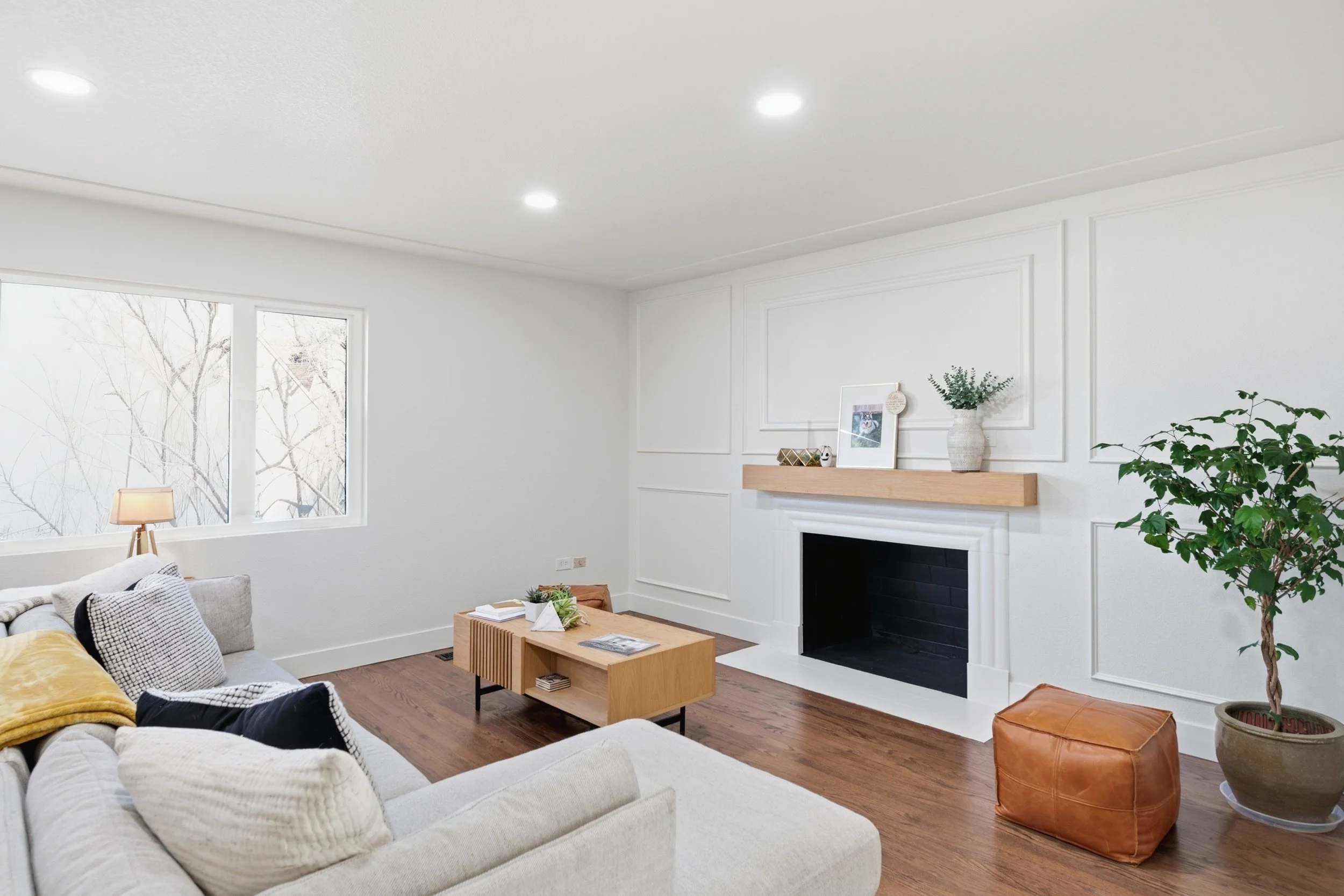 Renovated living room at 1735 Krameria Street in South Park Hill Denver, featuring a custom fireplace surround with board and batten detail, oak mantel, and refinished hardwood floors by The Rukavina Companies