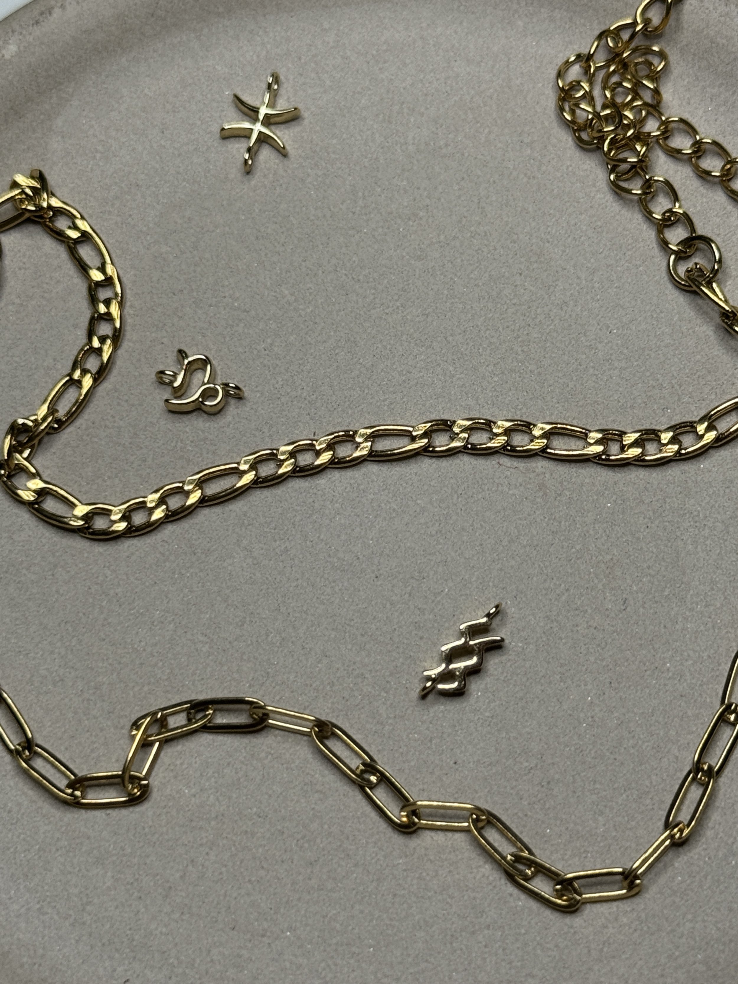 Gold chains, star-shaped and dollar sign-shaped jewelry pieces on gray background.