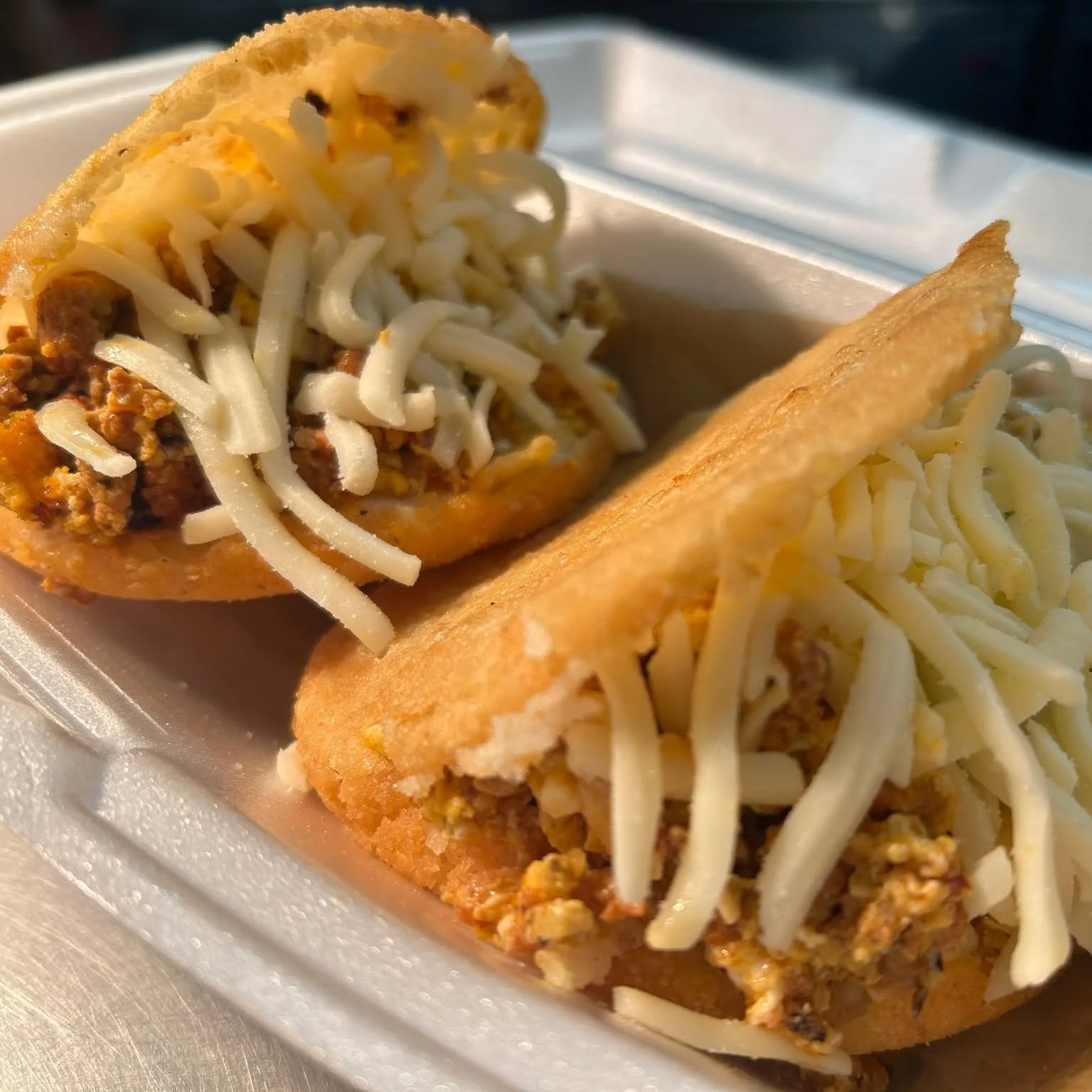 Close-up of two cheeseburgers in foam containers with cheese and ground beef patties