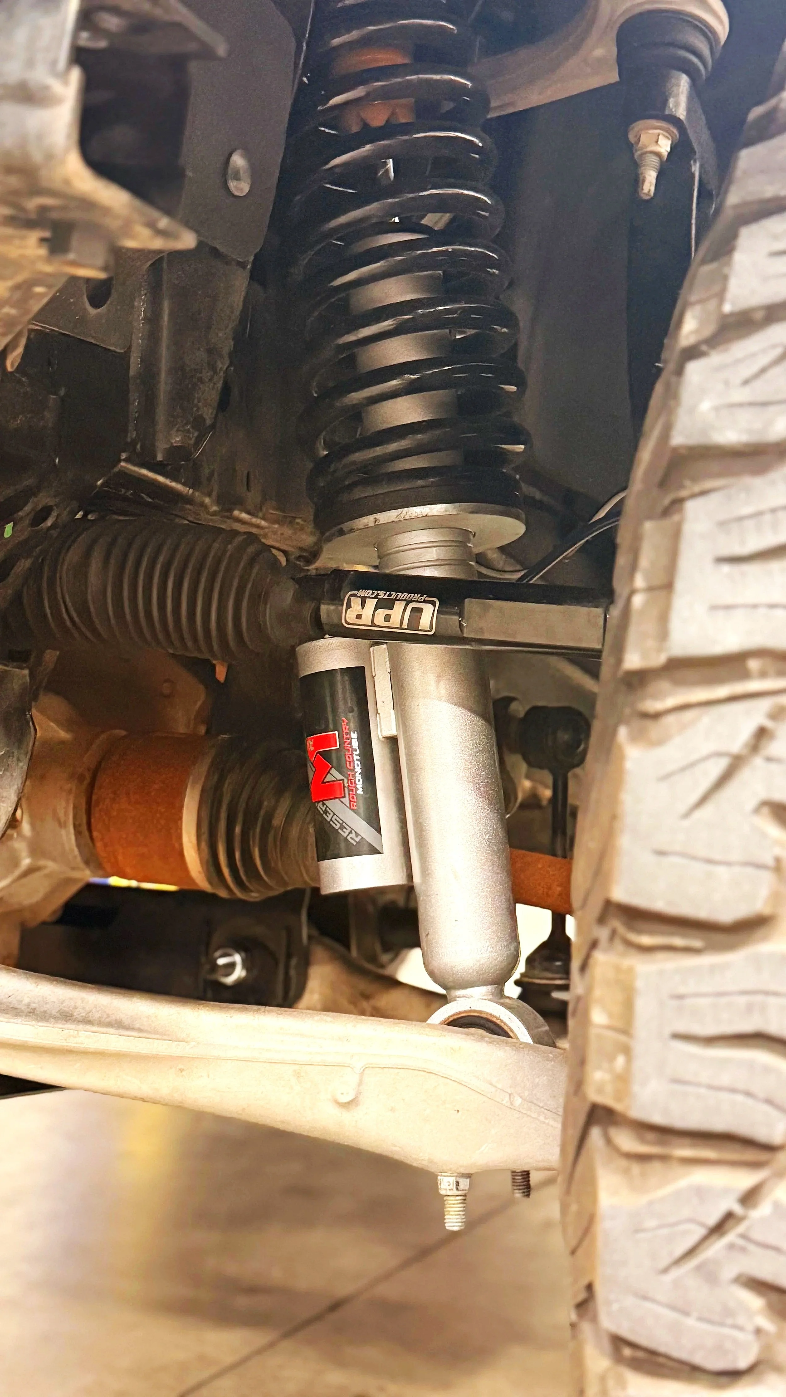 Close-up of a vehicle suspension system showing a coil spring, shock absorber, and tire tread.