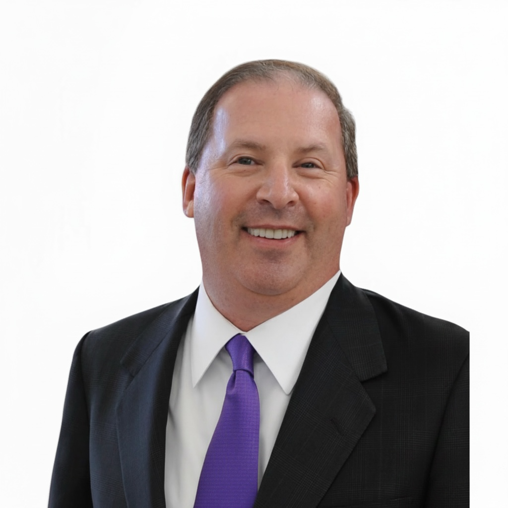 A smiling man in a business suit with a white shirt and purple tie, against a plain white background.