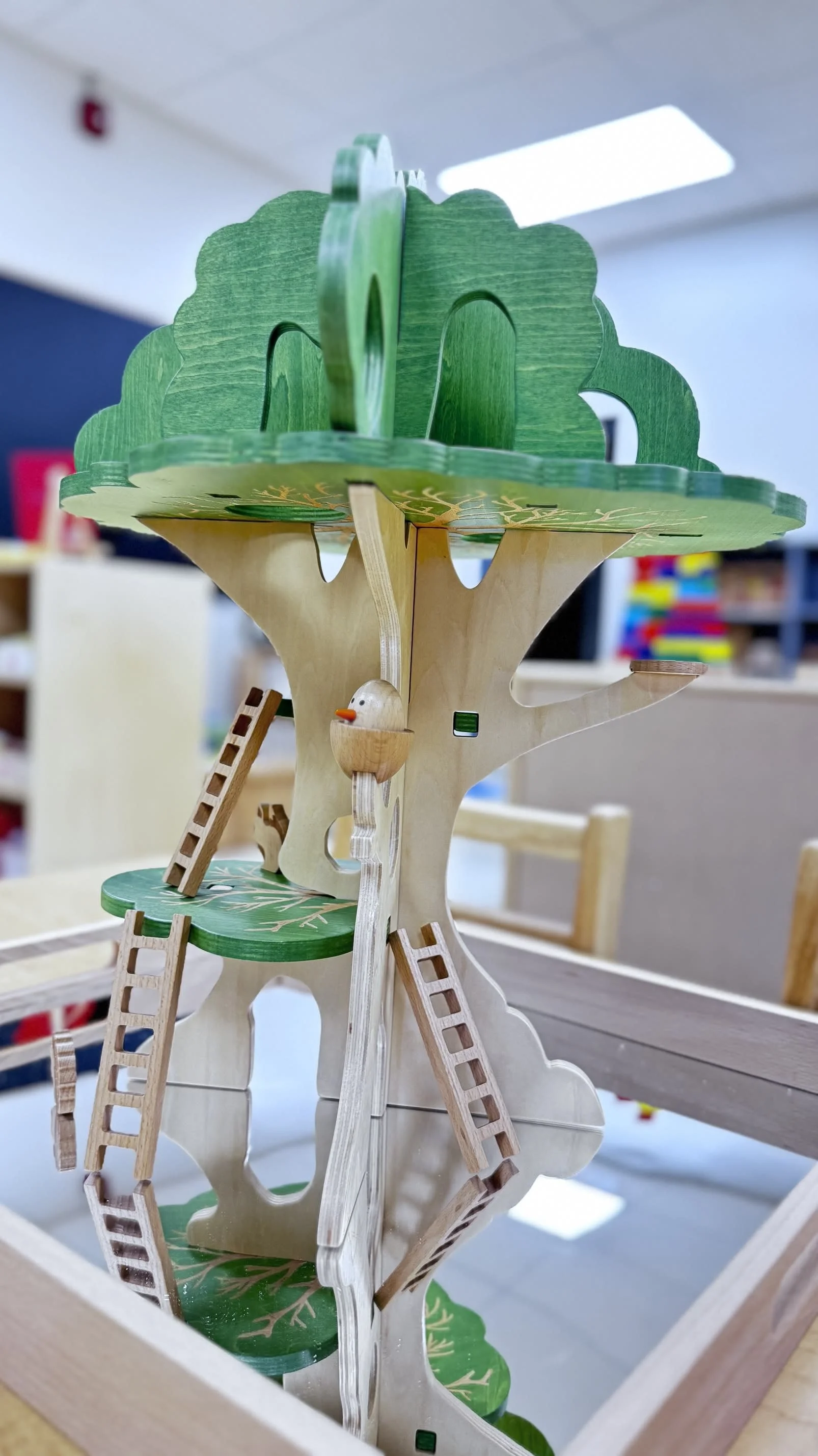 Wooden DIY tree model with ladders, a small bird figure, and green leaves, displayed inside a box.
