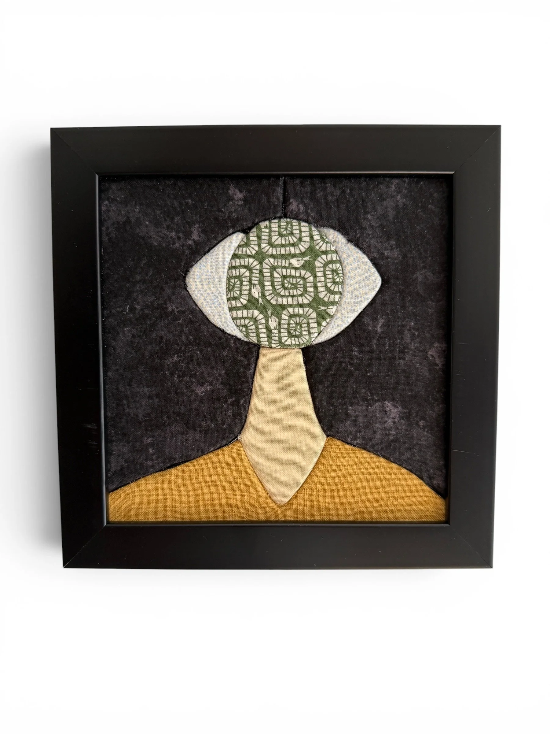Framed fabric artwork of a stylized face made in the Kinusaiga contemporary art technique on black background.