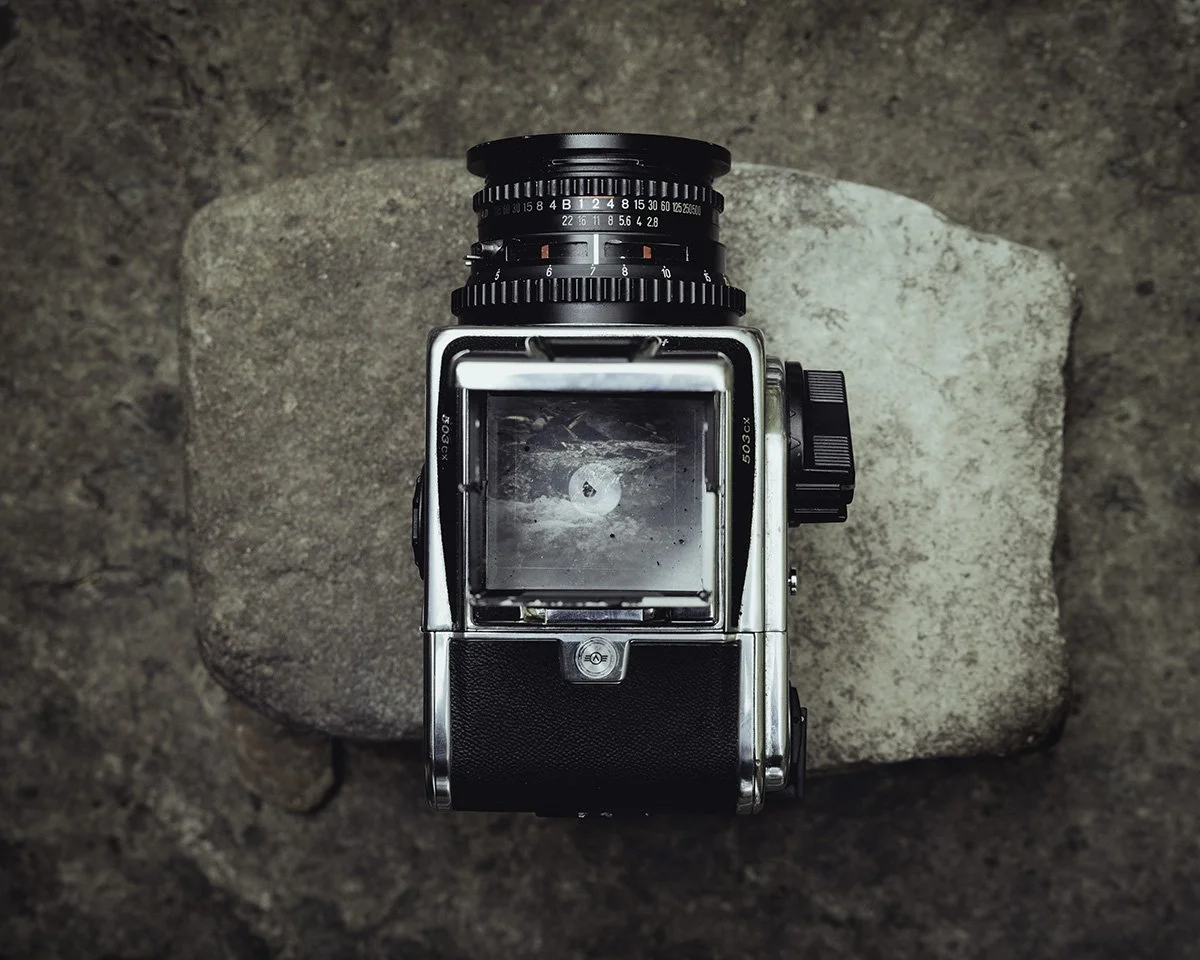 Vintage film camera placed on a large rock surface.