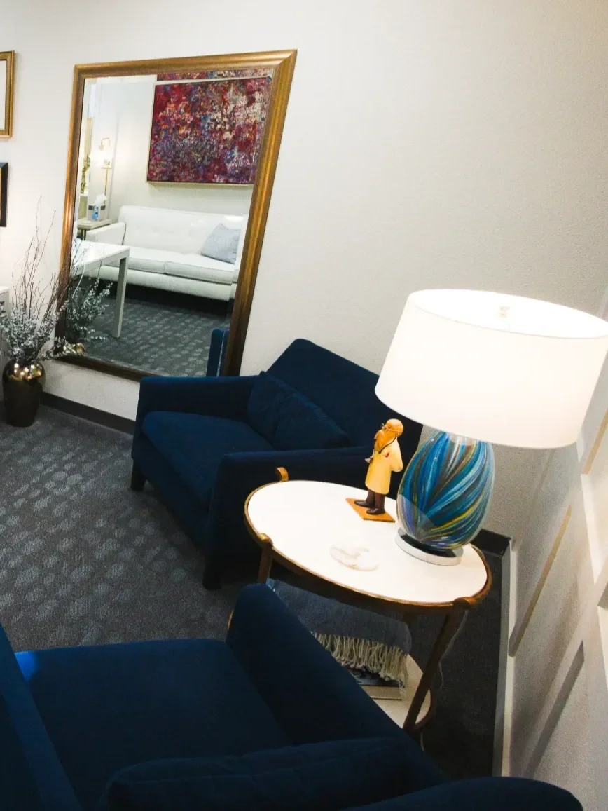 Concierge doctor's office with a navy blue sofa, a round side table, and a colorful lamp