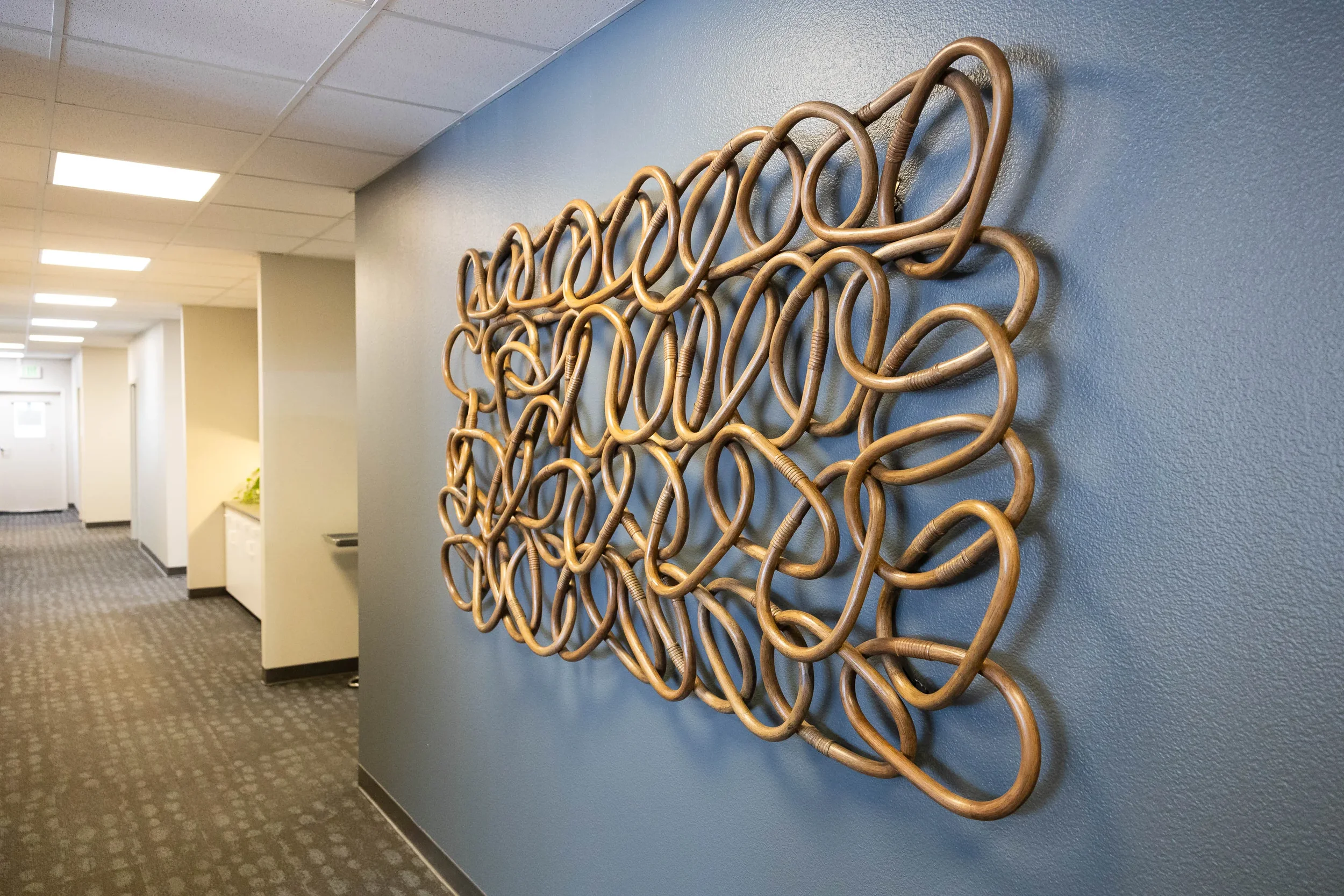 Wall decor made of intertwined gold metal loops mounted on a blue wall