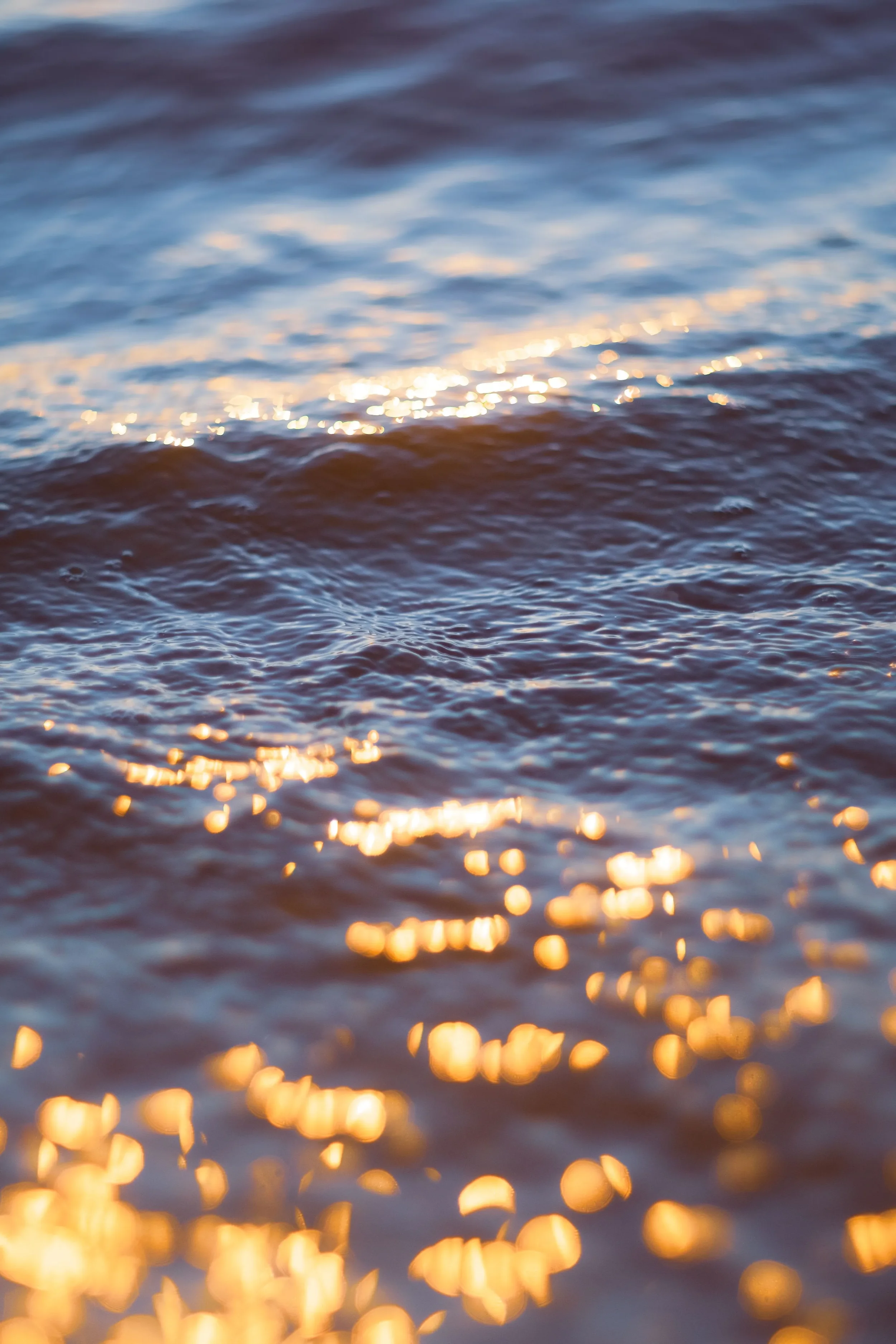 Blurred photo of a water surface with sunlight reflecting off the ripples.