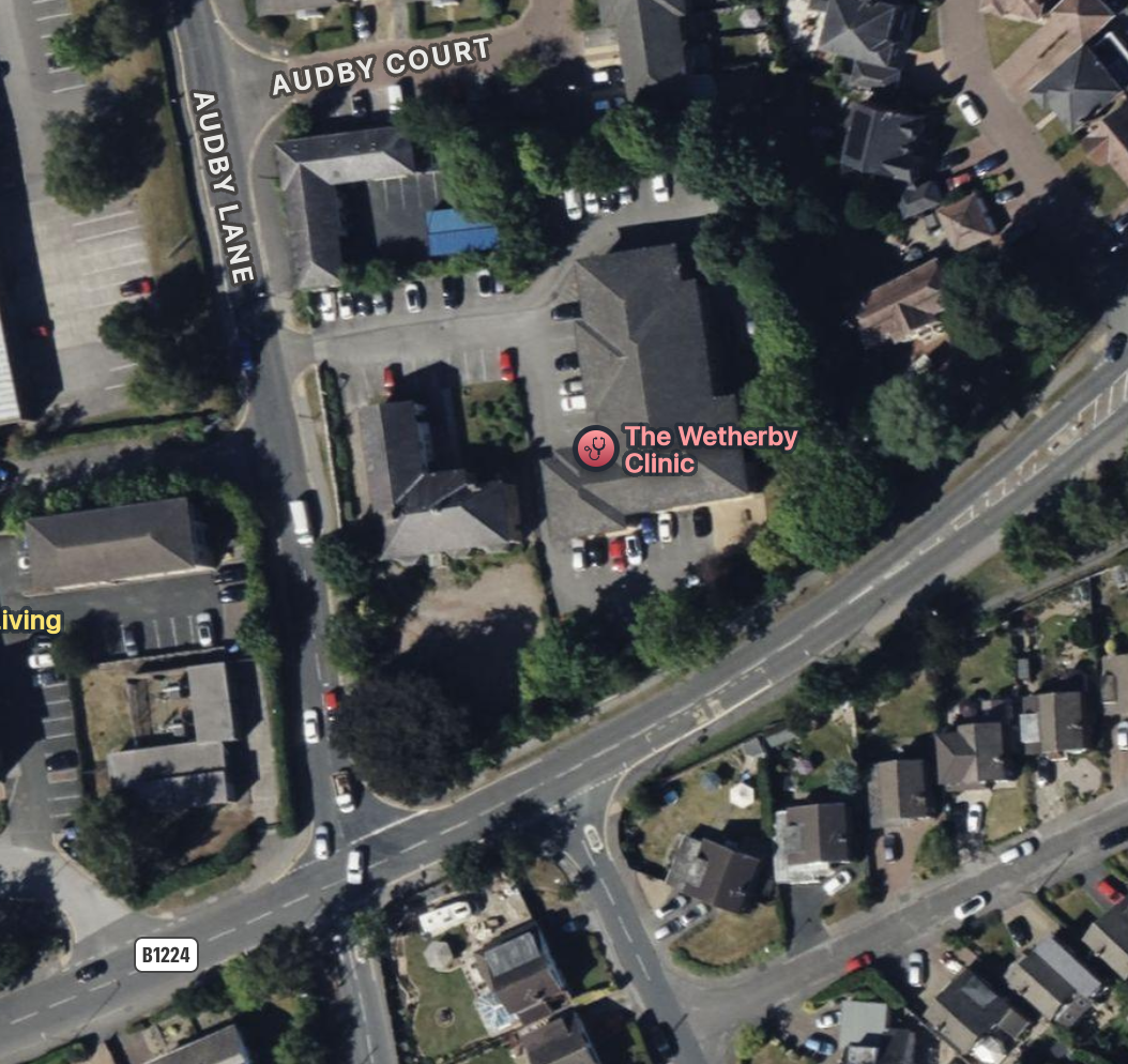 Satellite view of The Wetherby Clinic surrounded by trees and nearby residential houses, with a parking lot to the south and streets labeled Audby Lane and Audby Court.