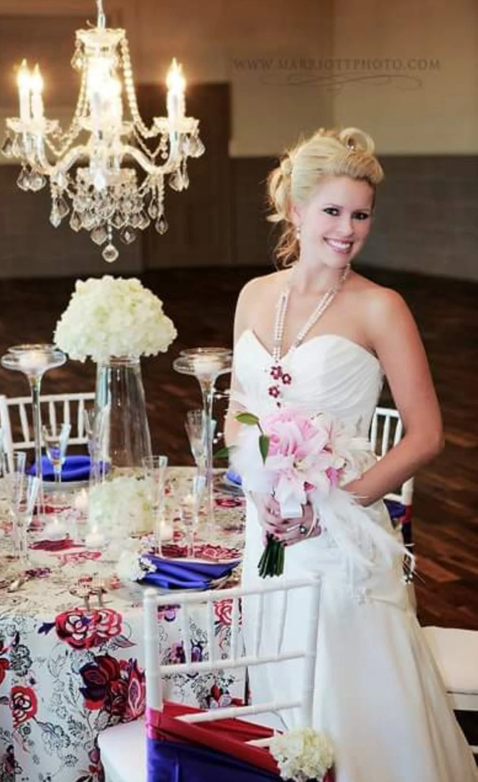 Bridal portrait at a wedding reception with a chandelier, floral centerpiece, and table settings.