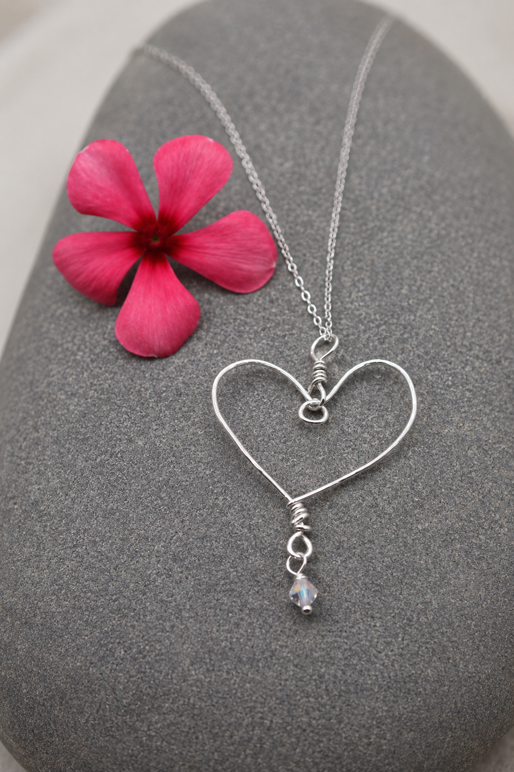 Live product photo of the Sterling Silver Heart Story Necklace, styled on a rock