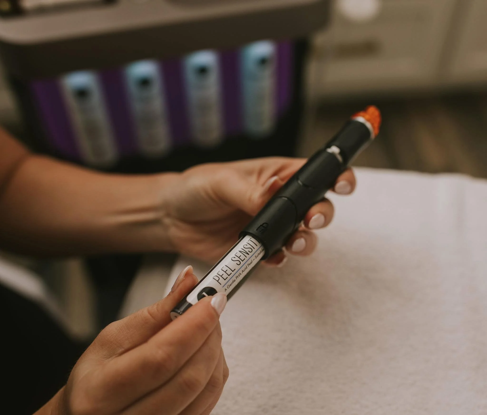Person holding a hydra facial device, inserting the peel into the hand piece.