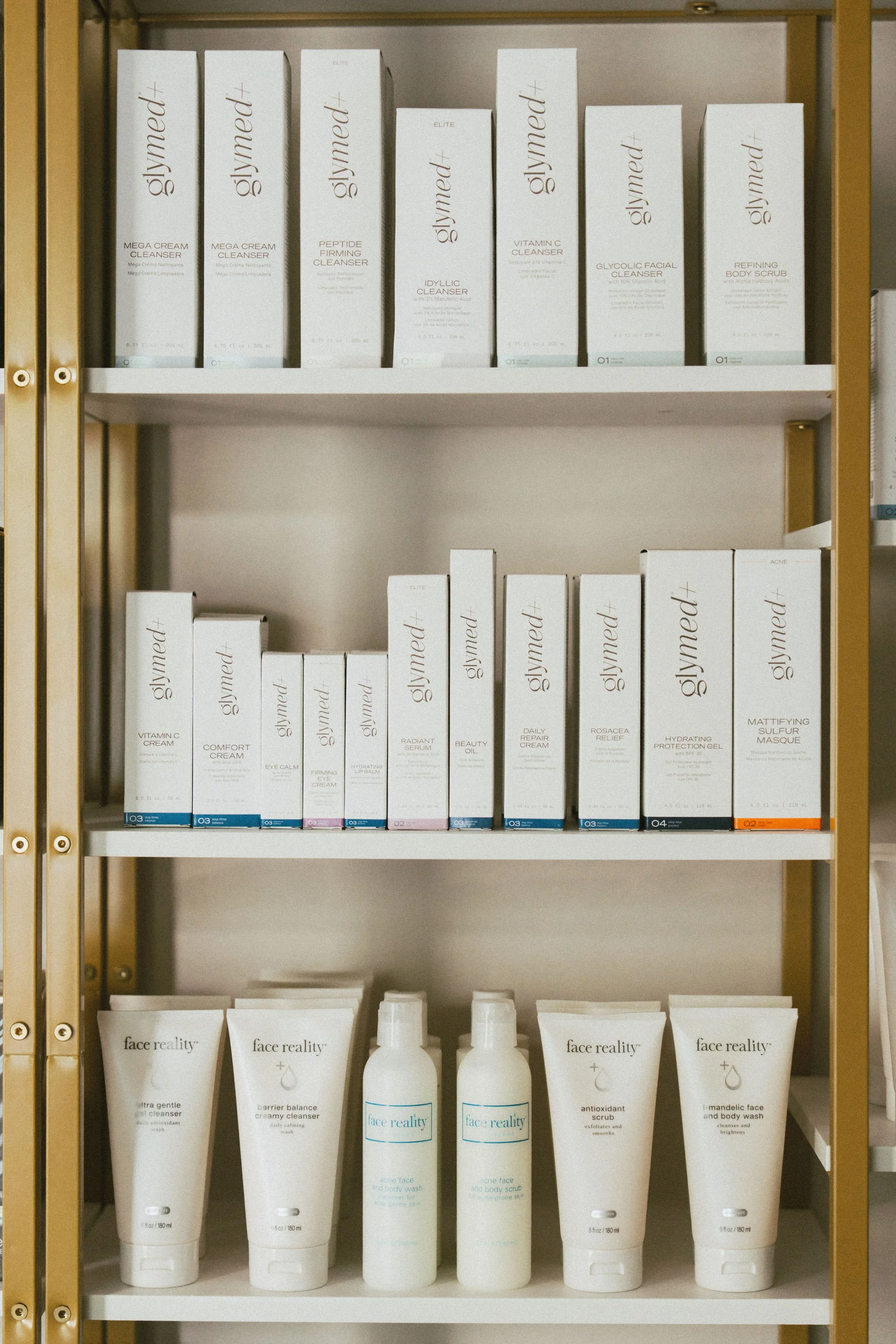 Shelf with skincare products, primarily from the brand Glymed, including cleansers, serums, and creams, organized in boxes and bottles.
