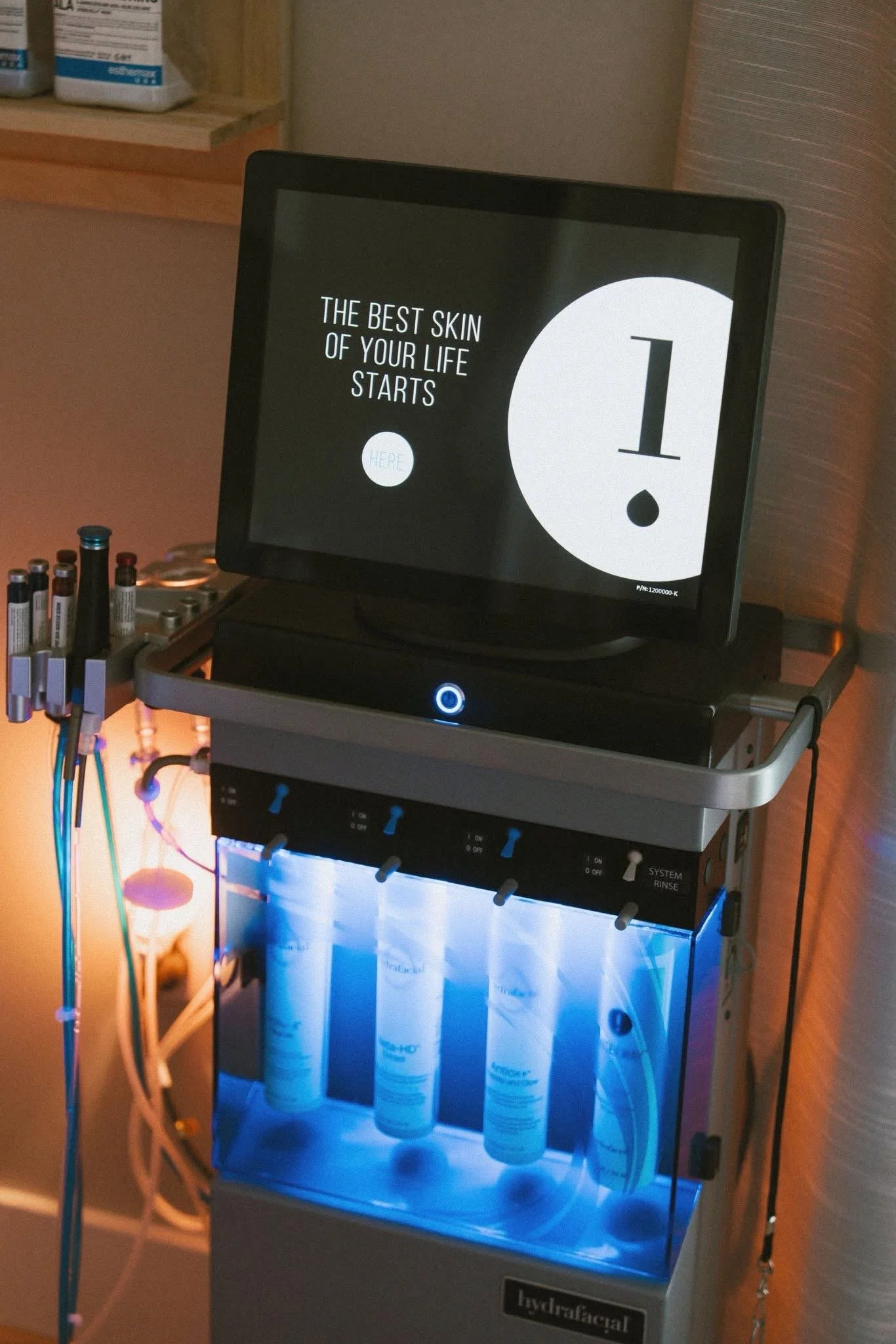 Hydrafacial machine in a skincare clinic with bottles of skincare products in the background.