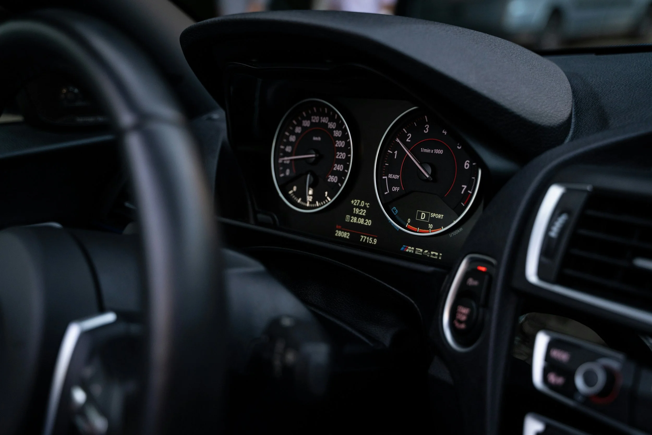 Close-up view of a car's dashboard and instrument cluster, including speedometer, tachometer, and digital display showing temperature, time, and date.