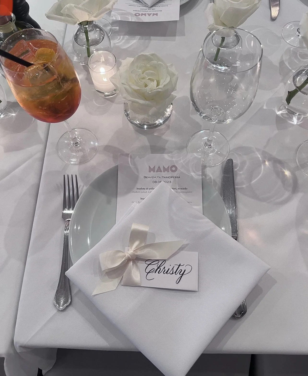 Calligraphy place card with cream colored ribbon and bow at bridal shower table place setting