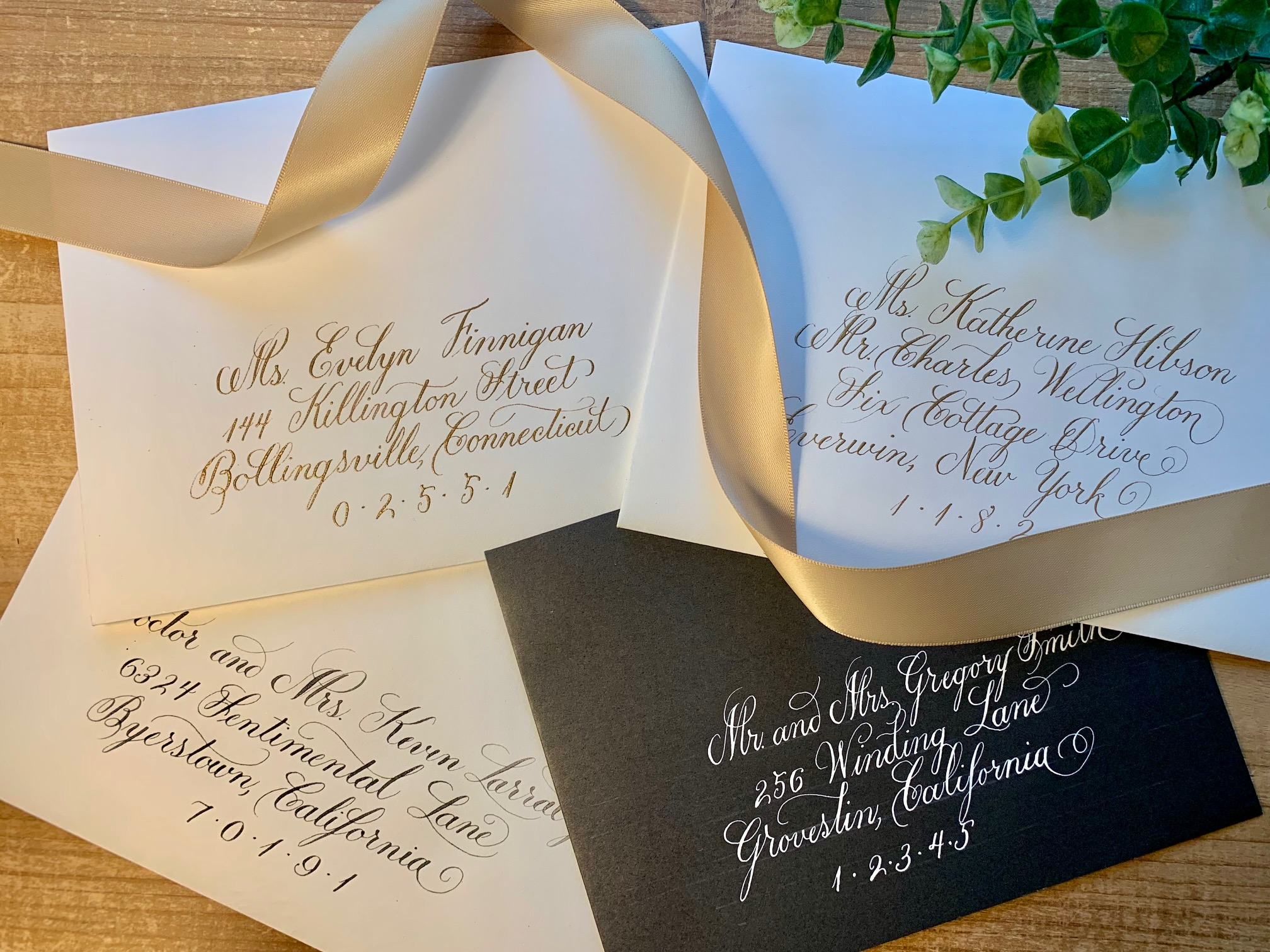 A collection of elegant, custom, personalized handwritten wedding envelopes addressed in formal calligraphy with gold, black, or white ink on cream, white, and black envelopes.