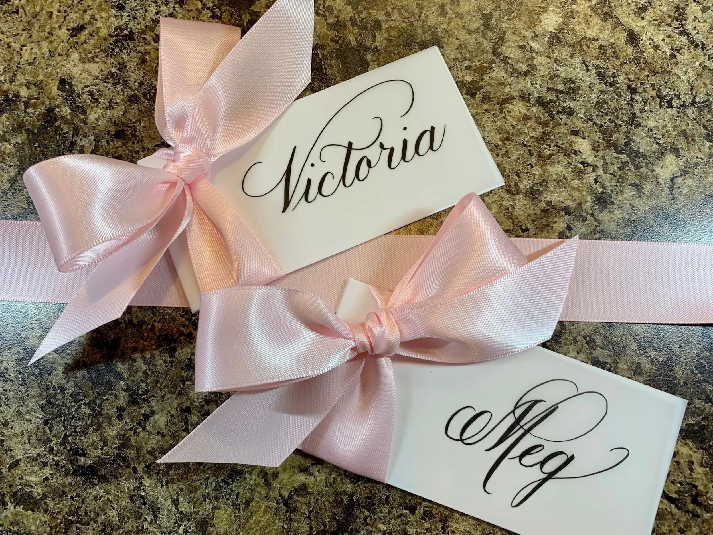 Calligraphy first name place card decorated with light pink ribbon and bow for wedding