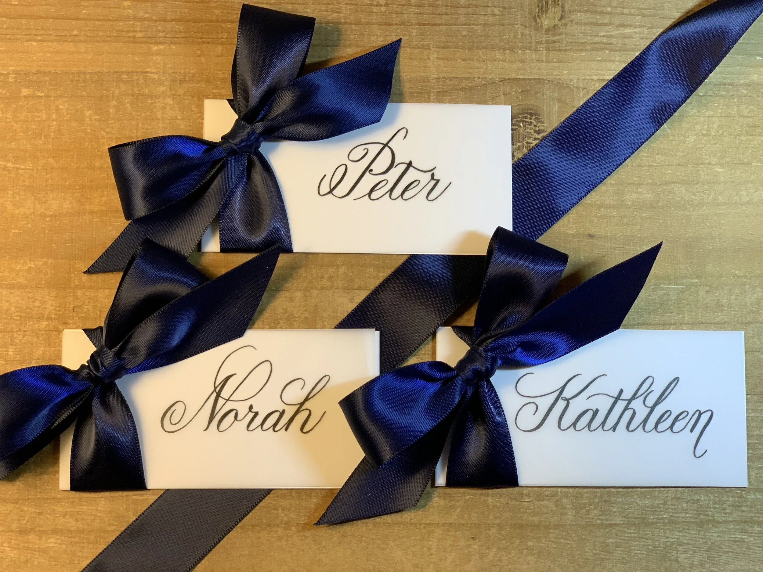 Navy blue satin ribbon place cards with handwritten names in calligraphy