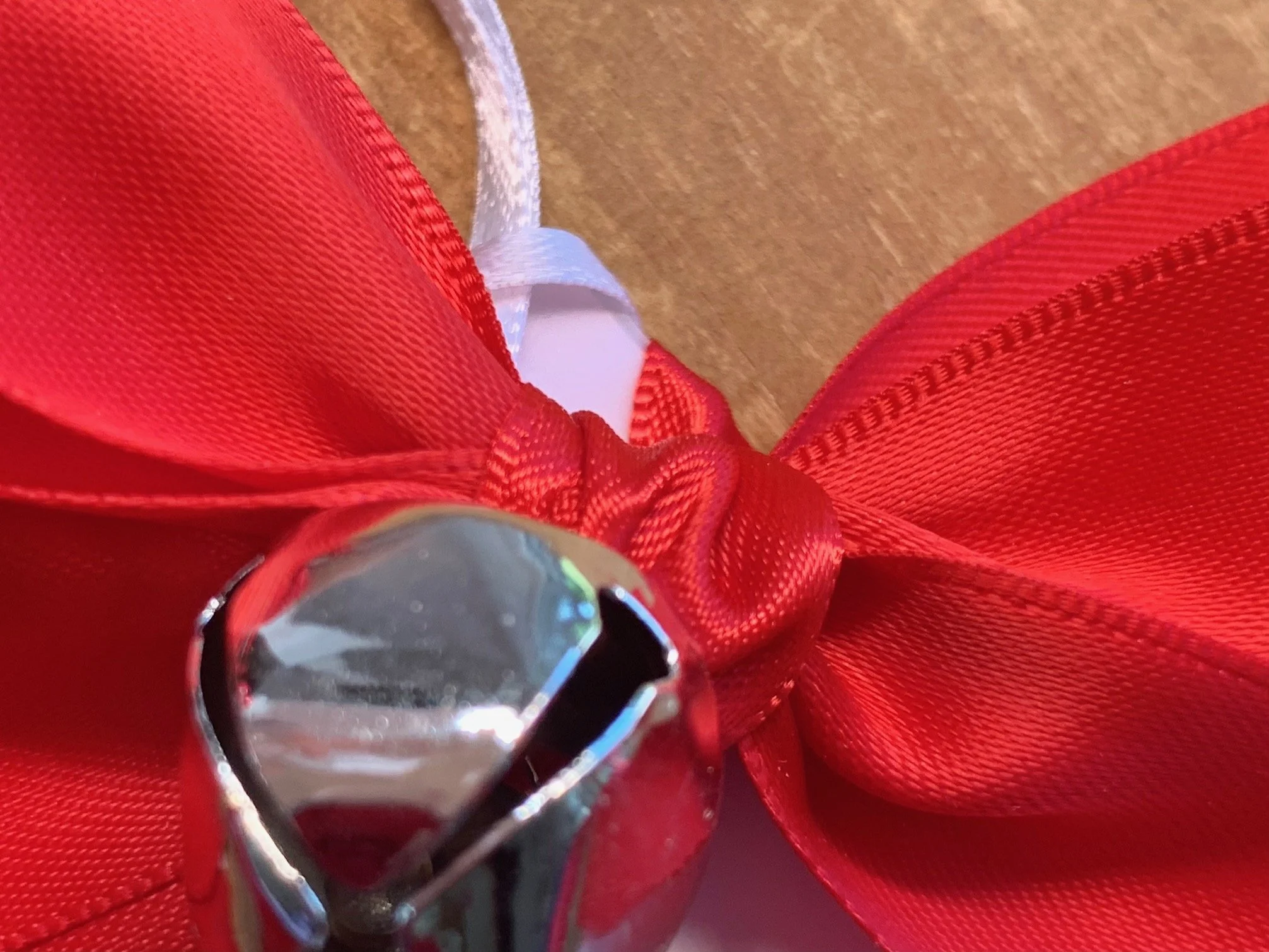 Christmas jingle bell gift tag with red satin bow and close up of white ribbon for tying to gift