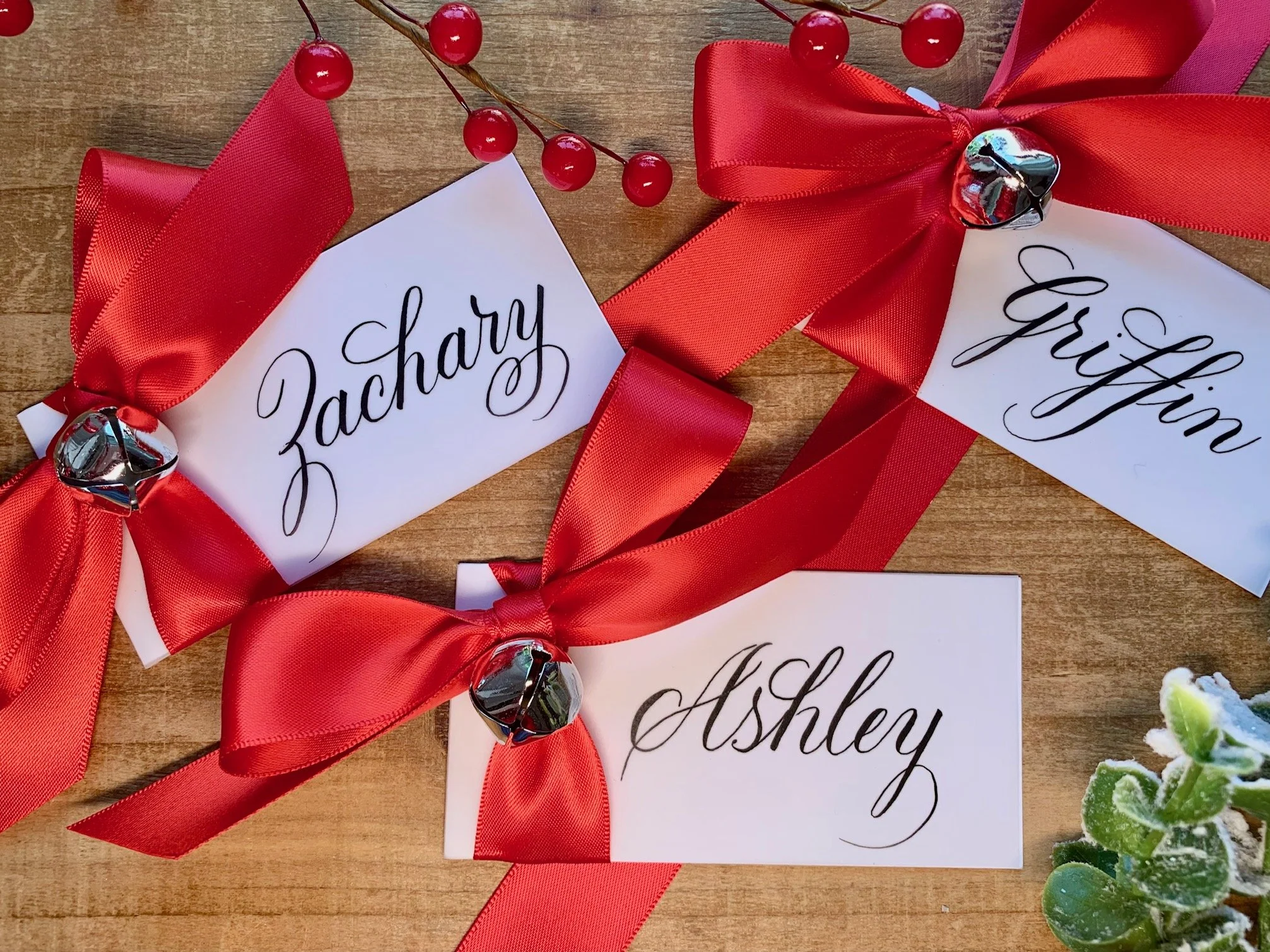 Christmas jingle bell place cards with red satin ribbon and personalized with handwritten calligraphy first names