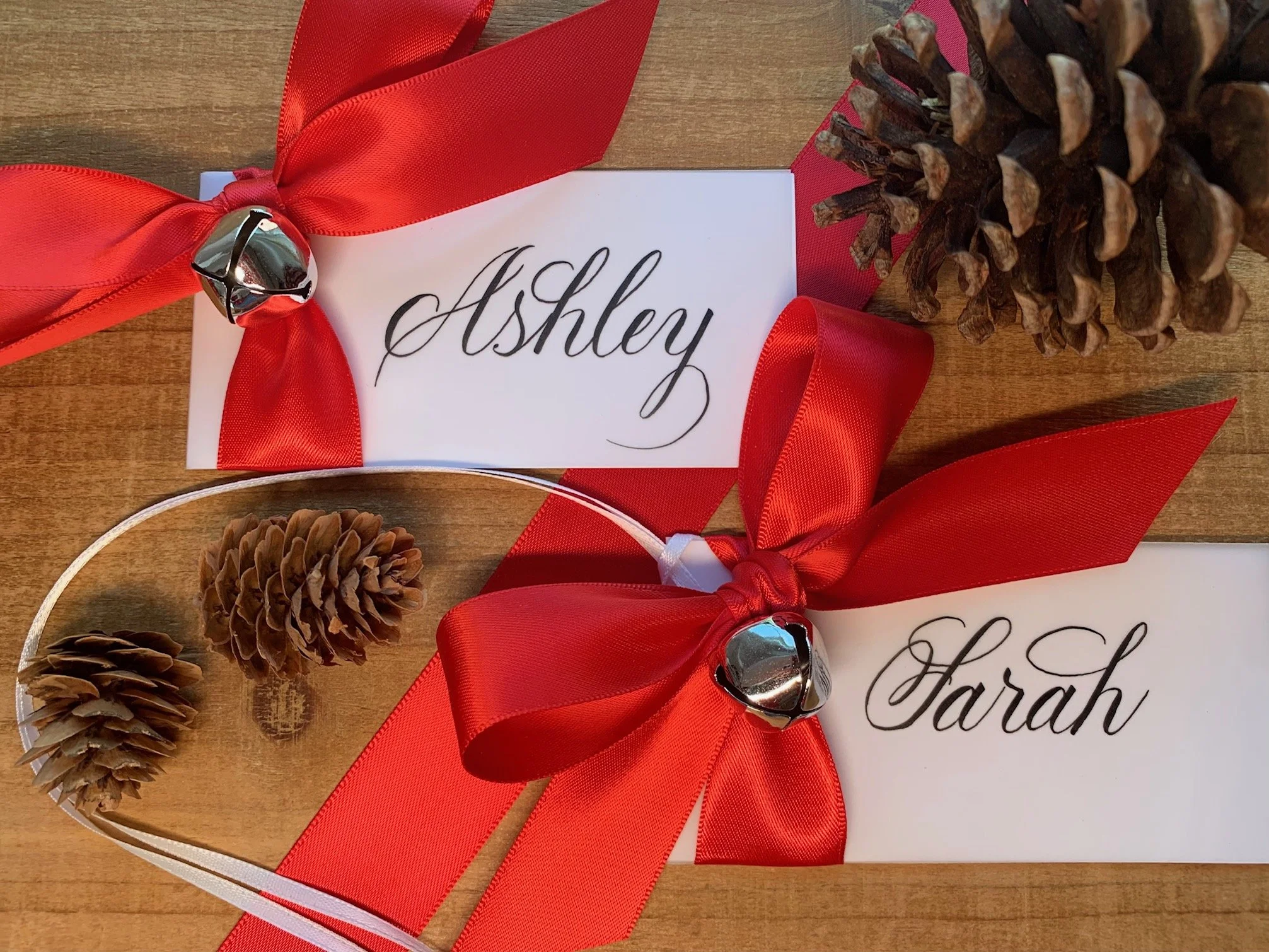 Christmas jingle bell place card and gift tag with red satin ribbon and personalized with handwritten calligraphy