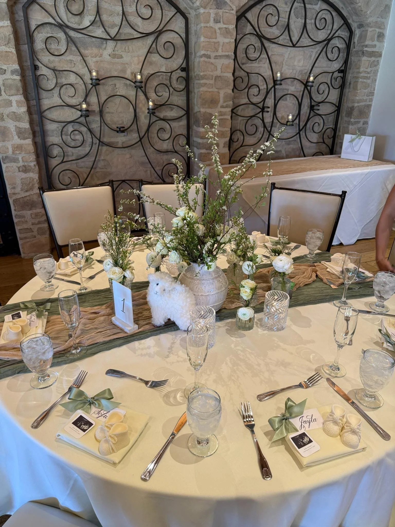Sage green ribbon on calligraphy place cards laying at place setting at baby shower