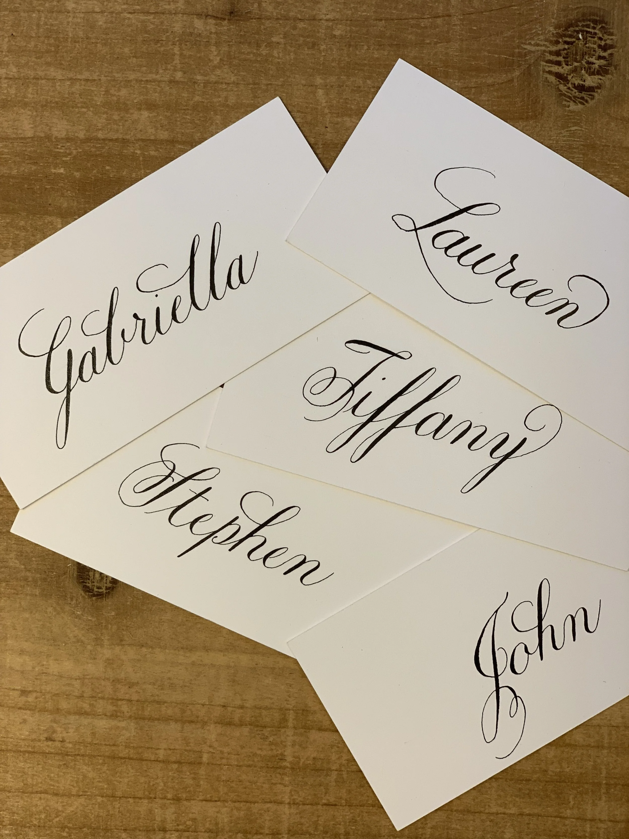Calligraphy place cards with custom personalization of first names in black ink.
