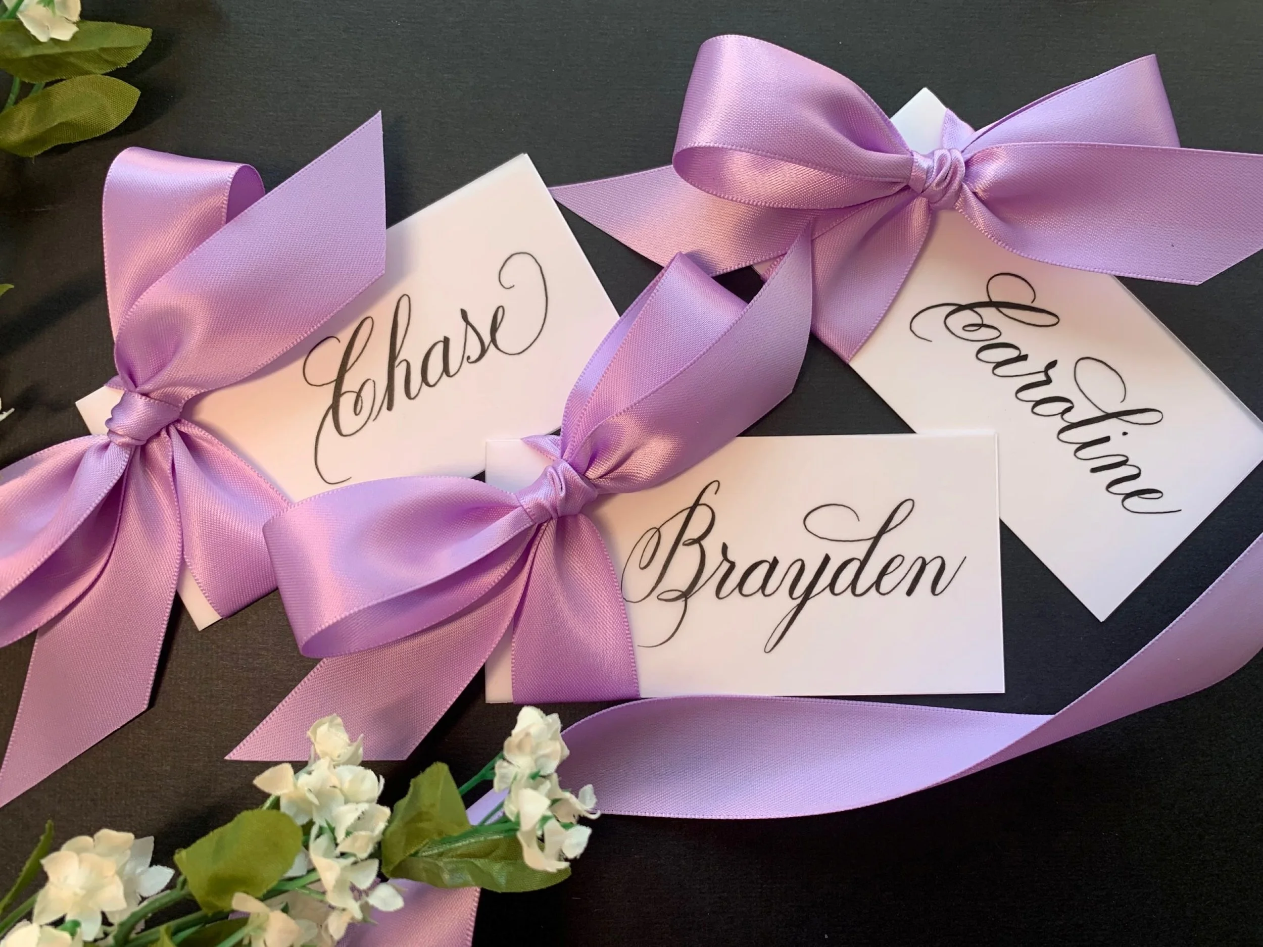 Satin lavender ribbon and bow place cards and gift tags with handwritten calligraphy. Personalized with names.