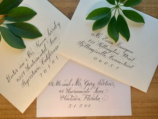 White and cream colored wedding envelopes with elegant black ink calligraphy handwritten address.