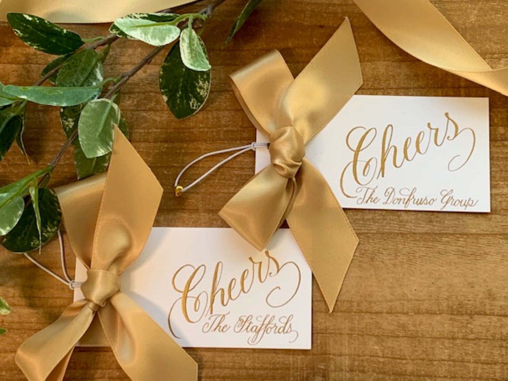 Gold wine bottle ribbon gift tags with custom calligraphy of personal name or business name for wedding favors or event gifts