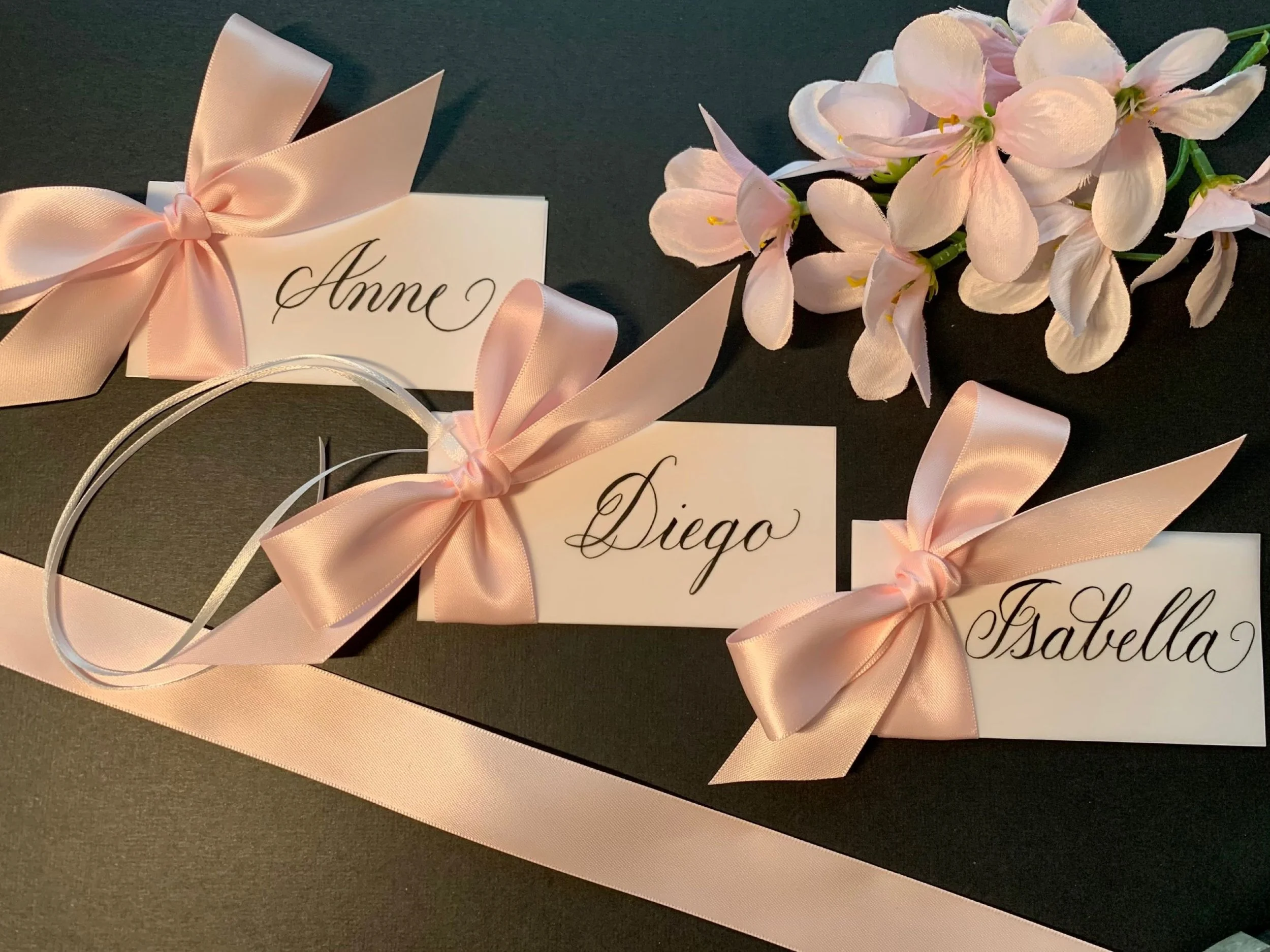 Calligraphy place cards and gift tag  with baby pink satin ribbon and bows for baby shower event