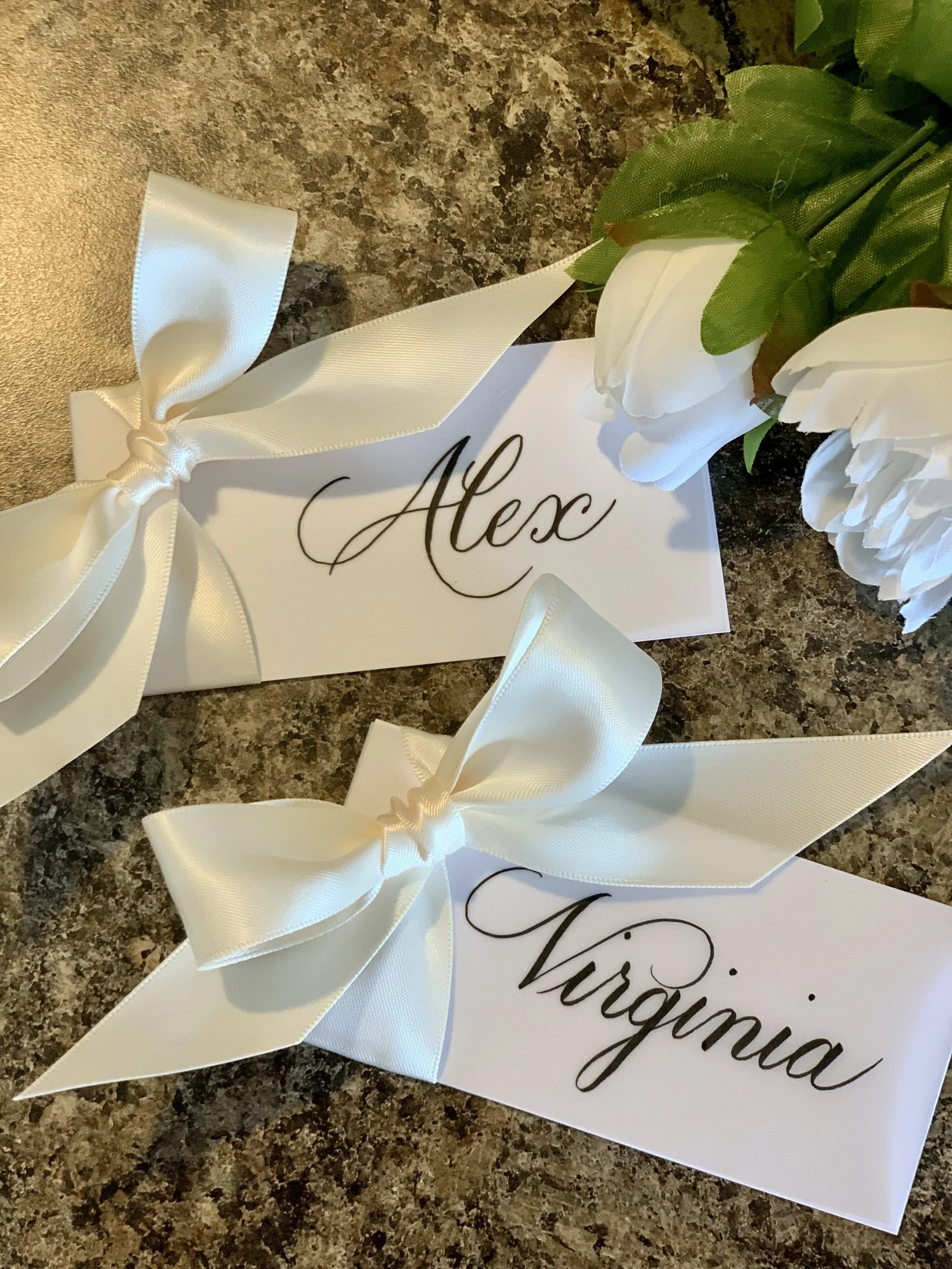 Handwritten calligraphy place cards with cream colored ribbon and bow