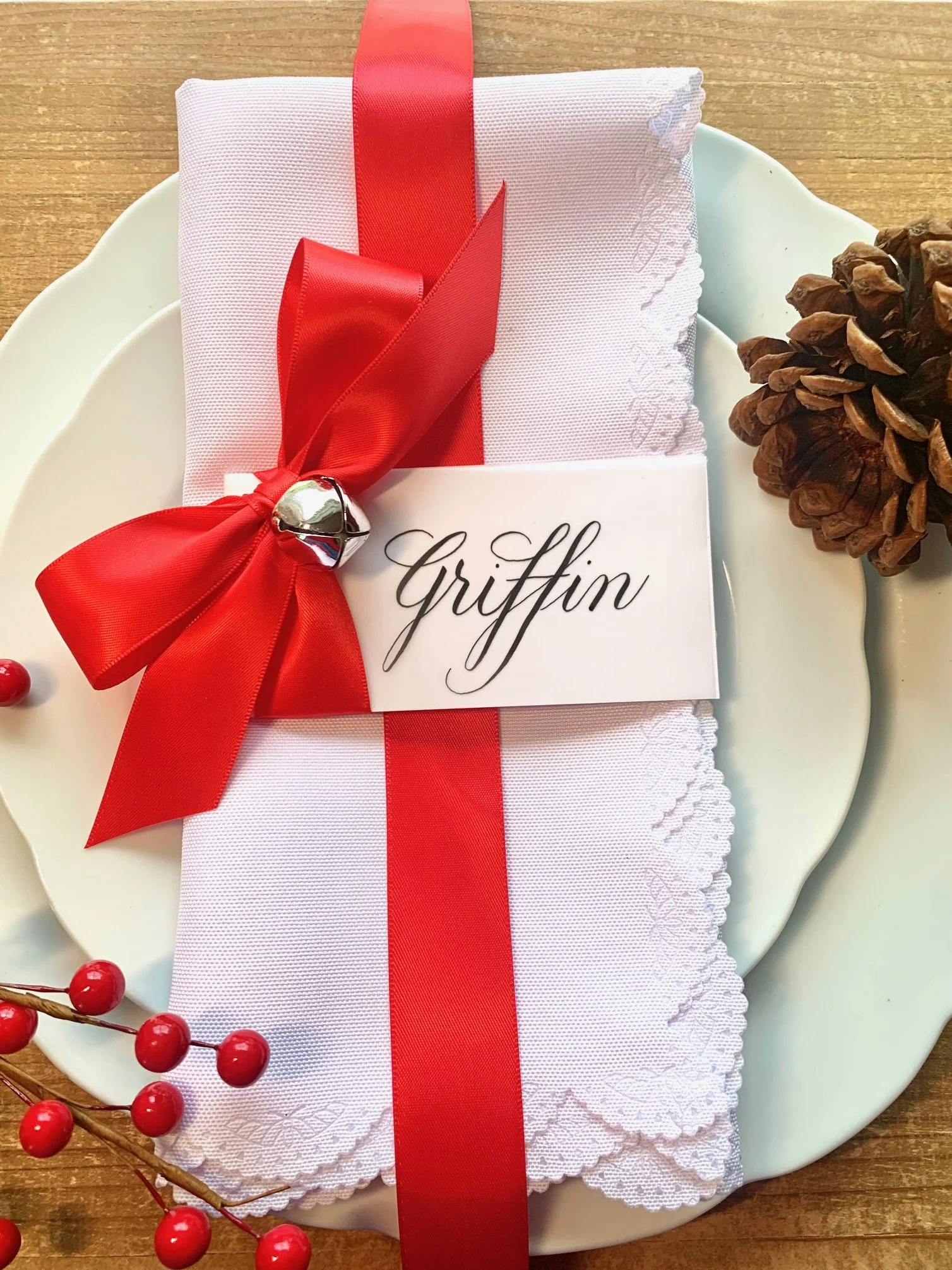Holiday place card with red ribbon bow and jingle bell with custom calligraphy handwritten name
