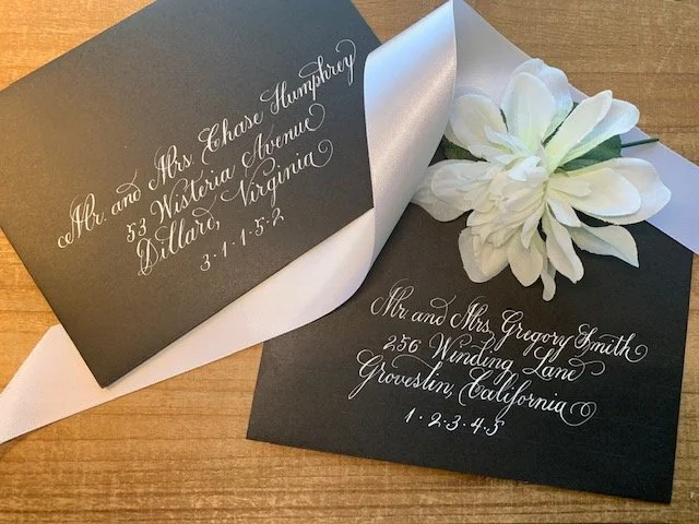 Wedding envelopes with handwritten calligraphy with white ink on black envelope.