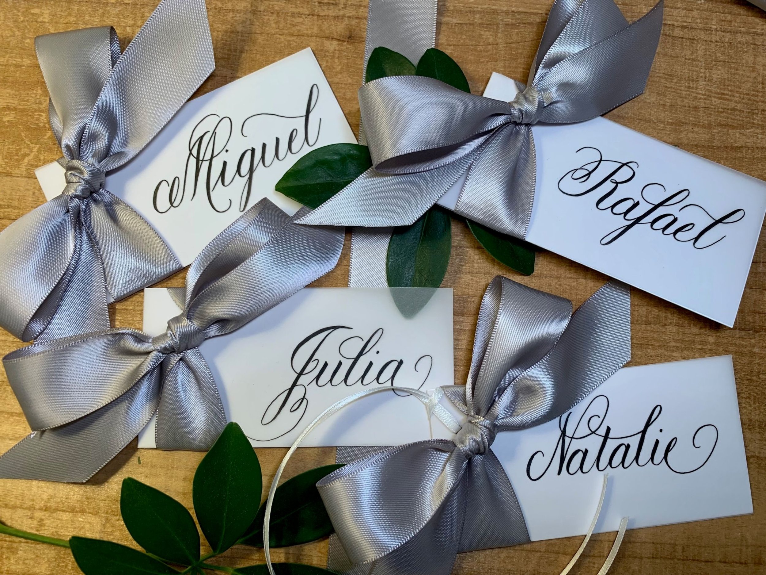 Calligraphy place cards with attached silver satin ribbon and bow
