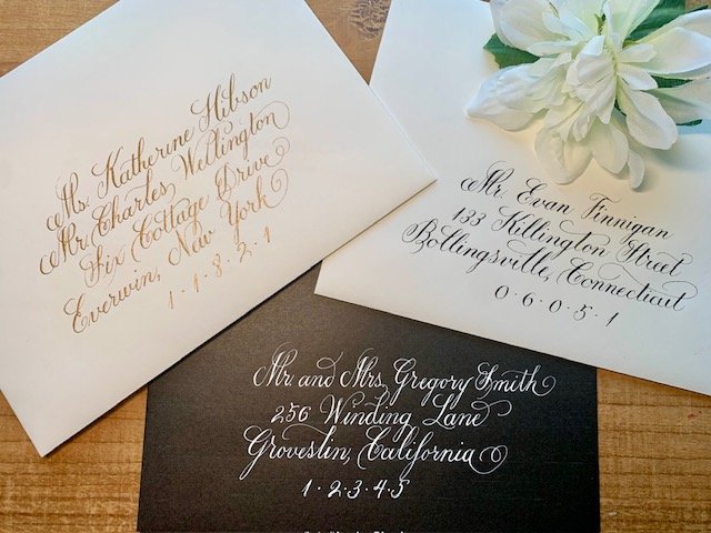 Handwritten formal calligraphy on wedding envelopes in gold, black, or white ink