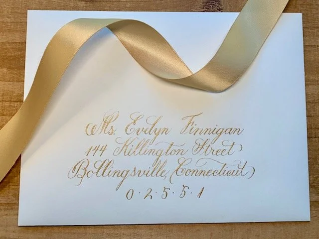 Cream colored wedding envelope with elegant gold ink calligraphy handwritten address.