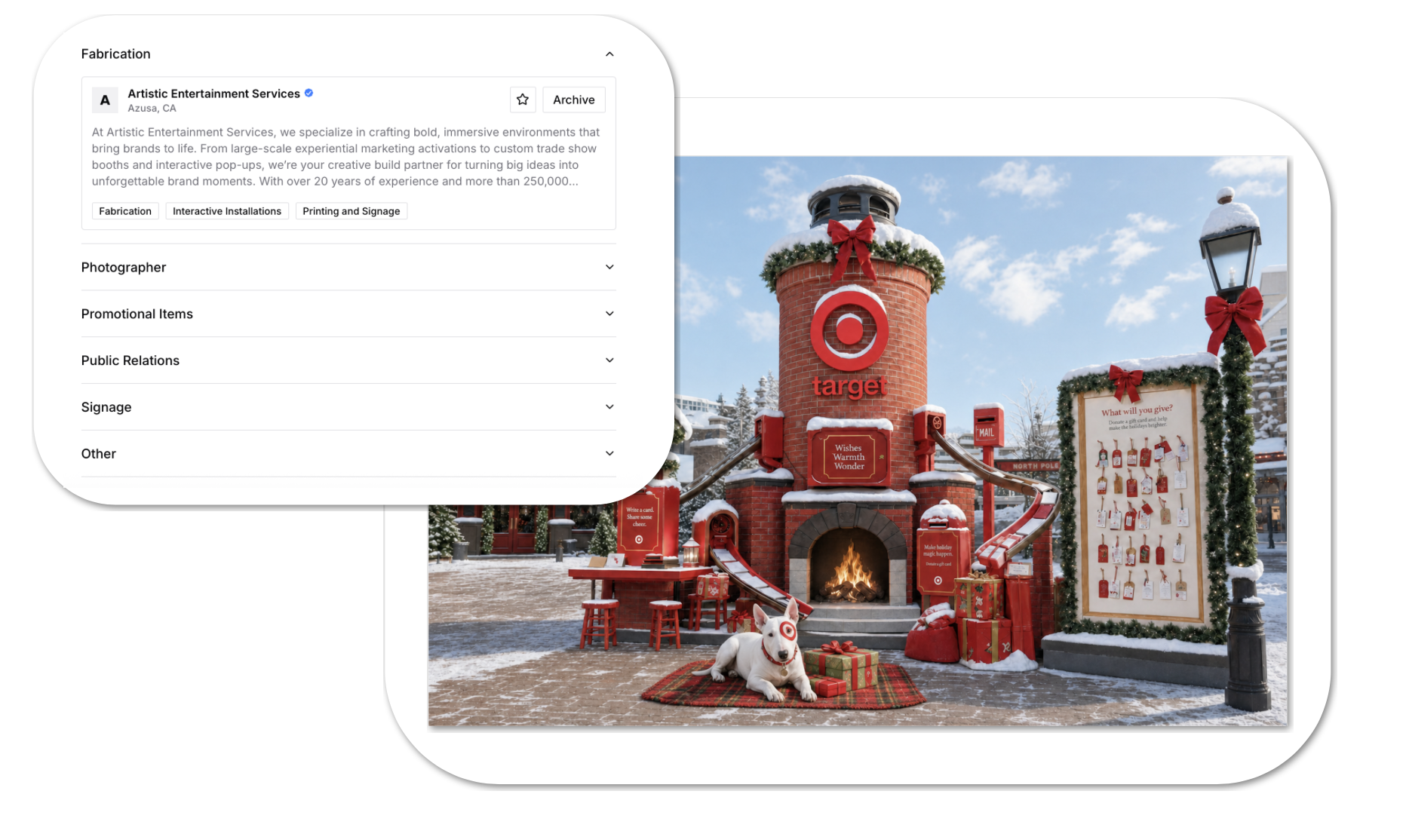 Outdoor festive scene featuring a Target store facade decorated for Christmas with red bows, greenery, and snow. A brick chimney-like structure with a red Target logo and a fire burning inside forms a central feature. There are red gift boxes, a small table with red stools, and a white dog wearing Target-themed glasses sitting on a red plaid blanket surrounded by gifts. The scene is wintry with snow on the ground, lamp posts, and decorations.