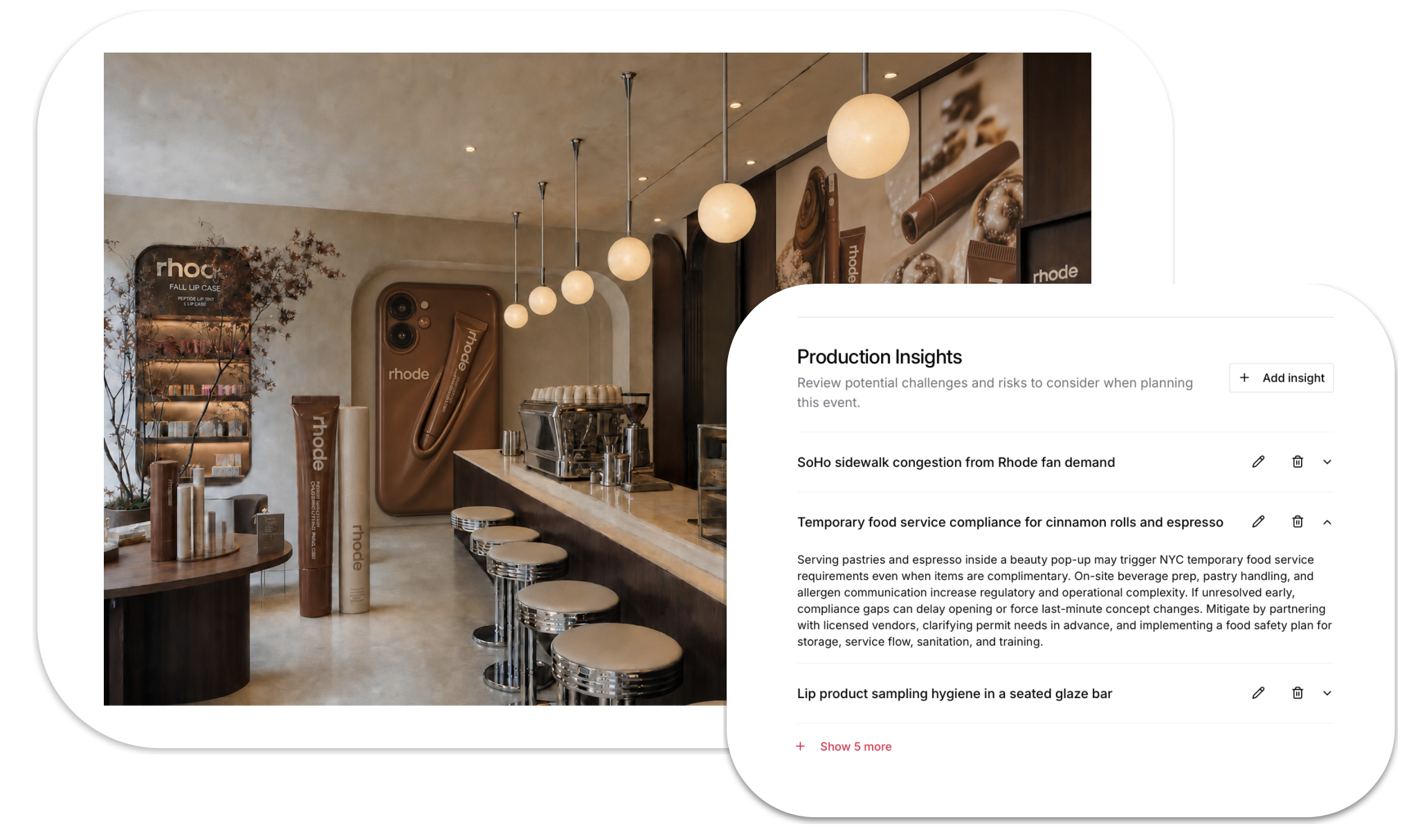 Interior of a modern cafe or coffee shop with warm lighting, featuring a bar area with stools, round pendant lights hanging from the ceiling, and decorative wall panels with branding and product images related to Rhode, a lip product brand.