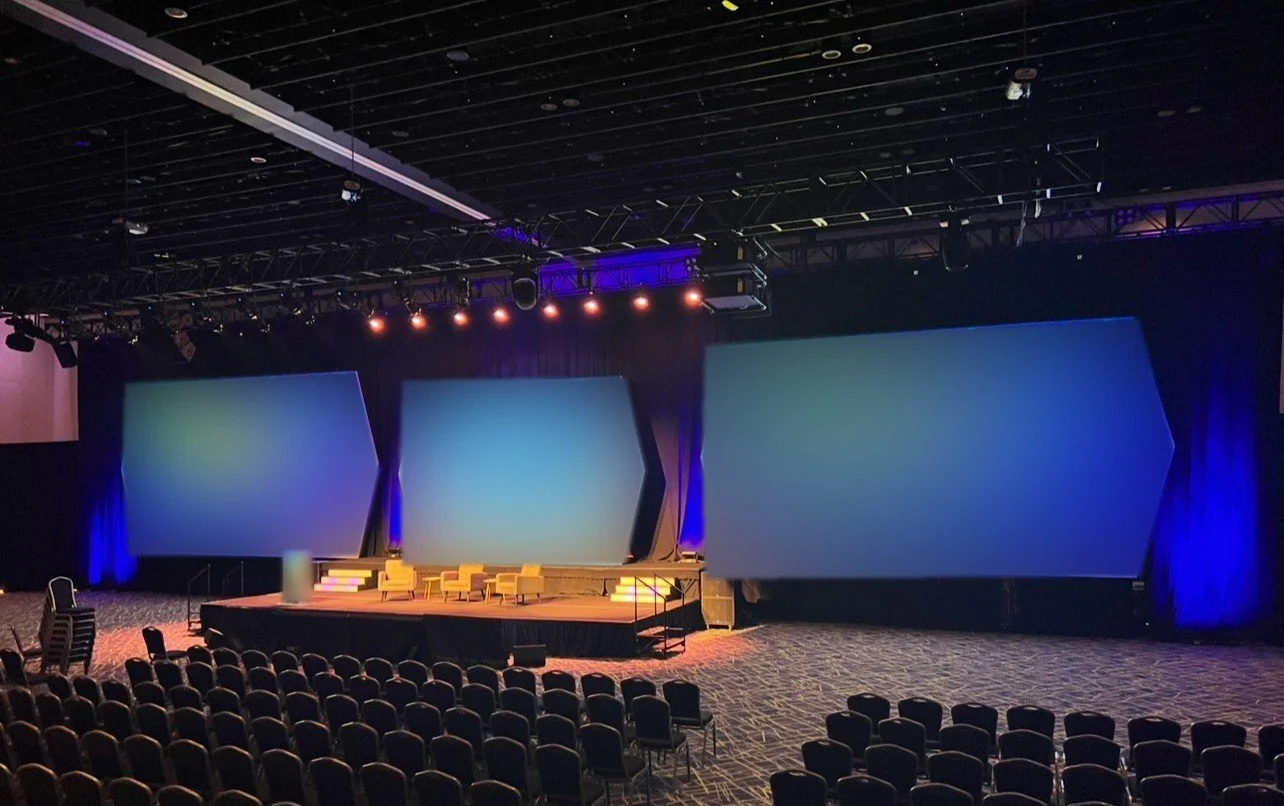 Three screen general session with custom angled LED surrounds and a soft seating stage