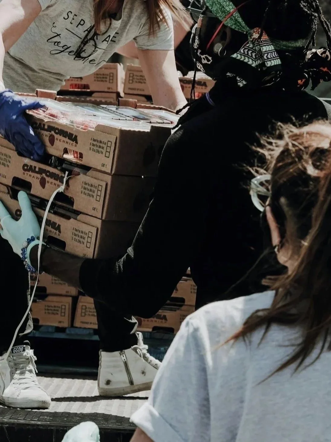 Group of people loading or unloading boxes of strawberries in an industrial or warehouse setting.