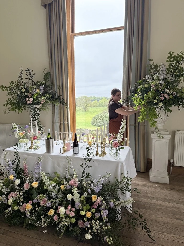 Large floral meadow installation alongside two large urn arrangements framing the sweetheart table at Springkell. All of the designs were repurposed from the ceremony.
