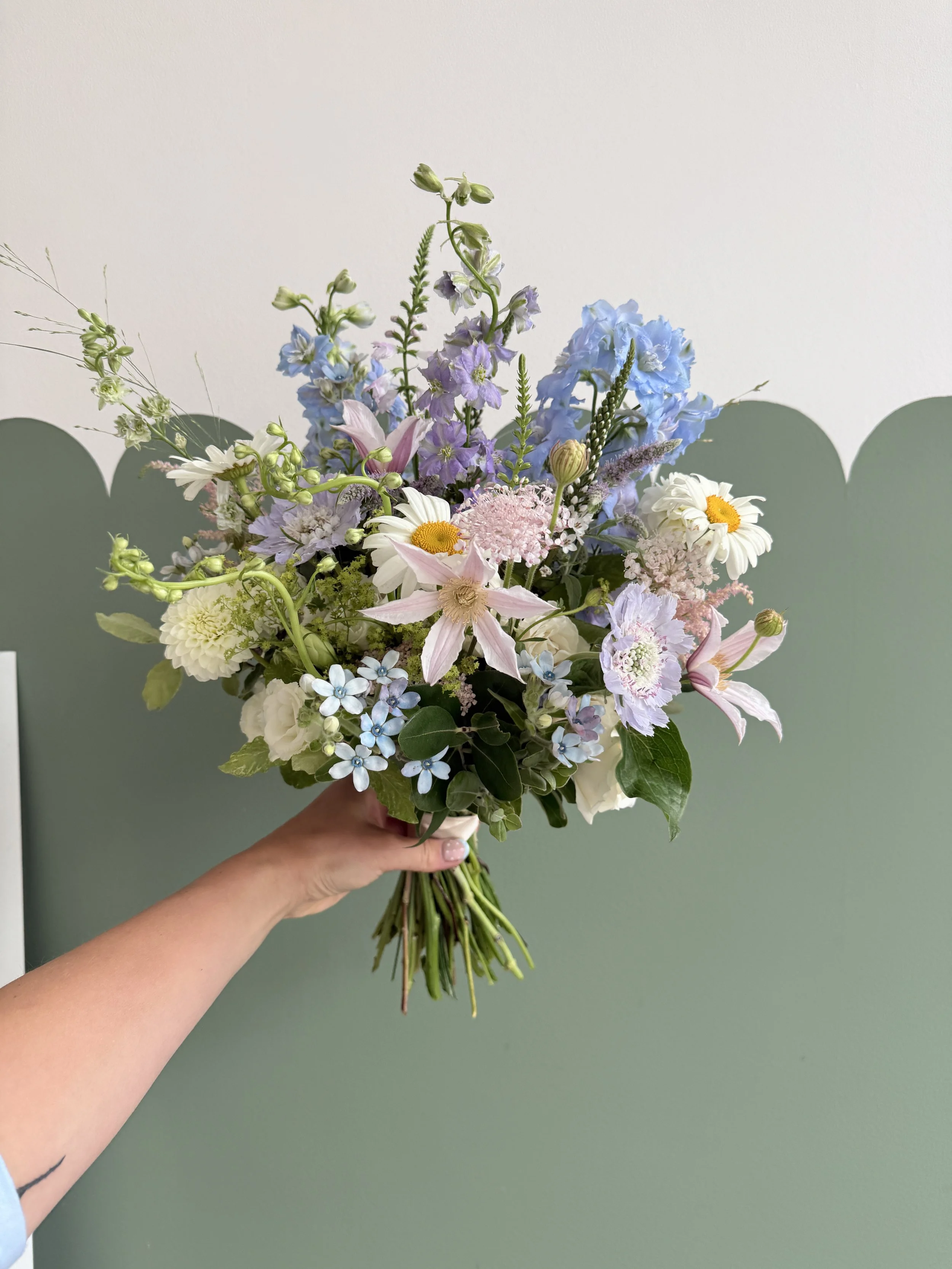 Garden style bridal bouquet featuring Delphiniums, Daisuies, Dahlia and Clematis.