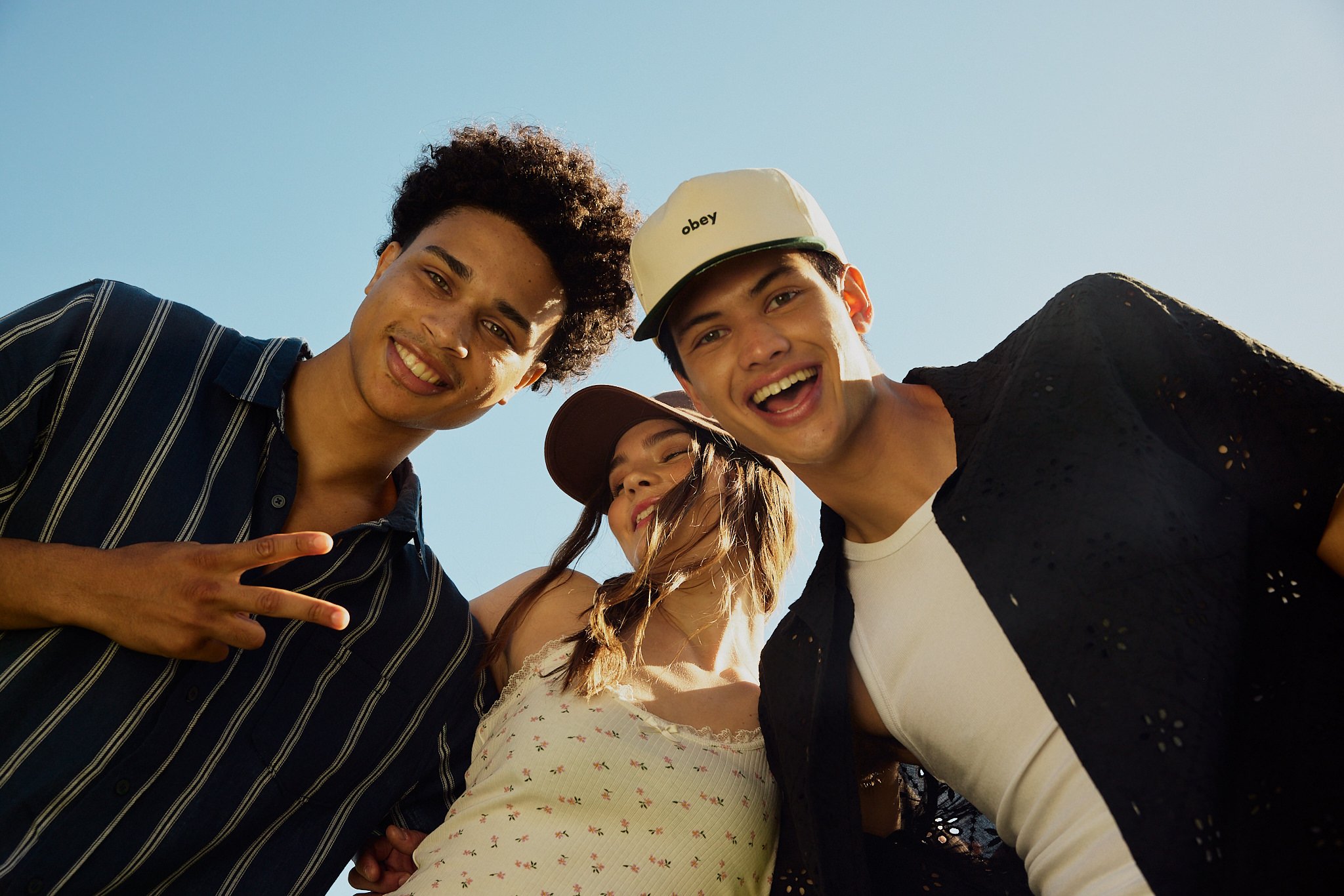 A group of young friends taking a selfie outside on a sunny day, smiling and enjoying each other's company.