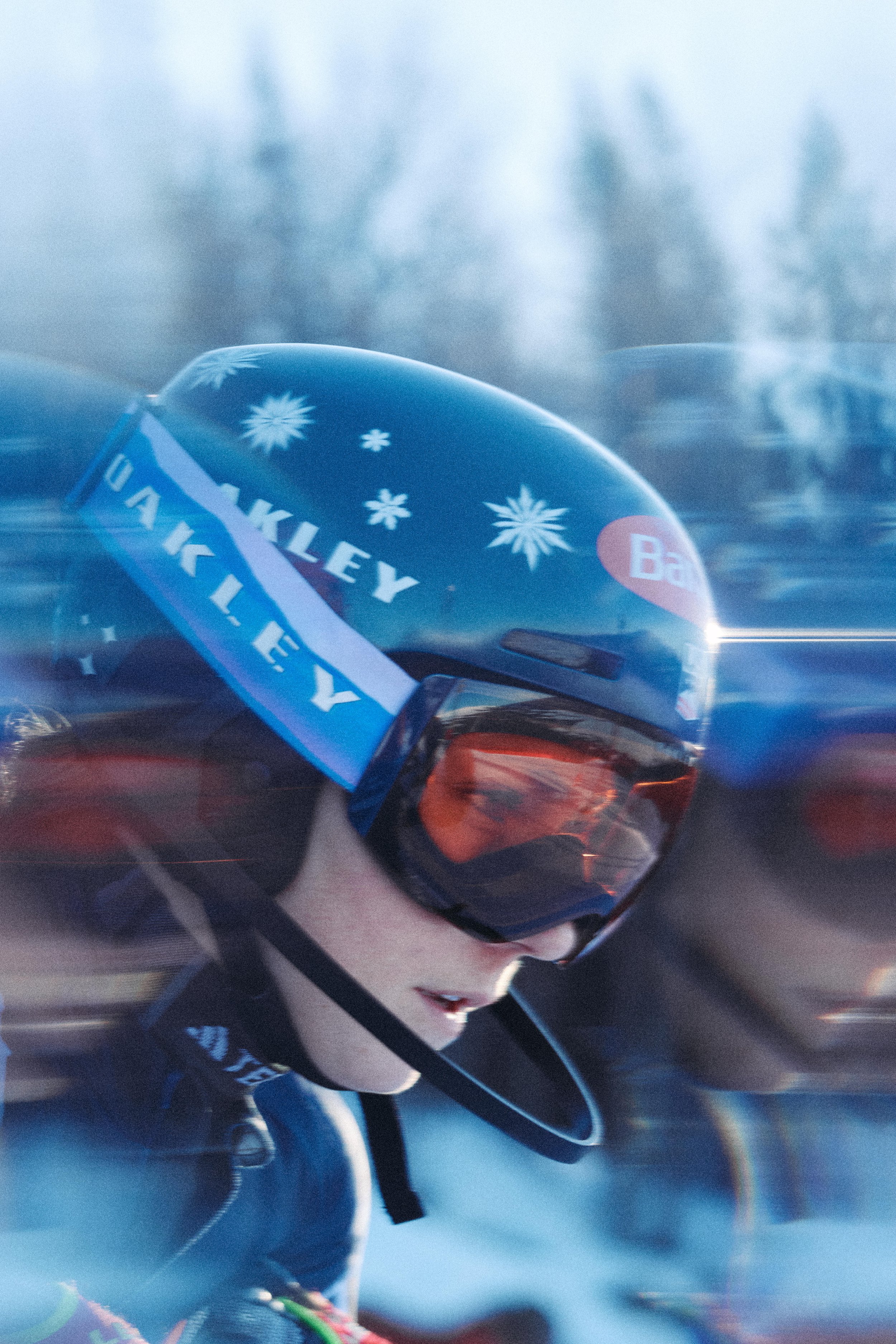 A young female skier with goggles and a helmet, snowboarding or skiing in a snowy landscape during winter.