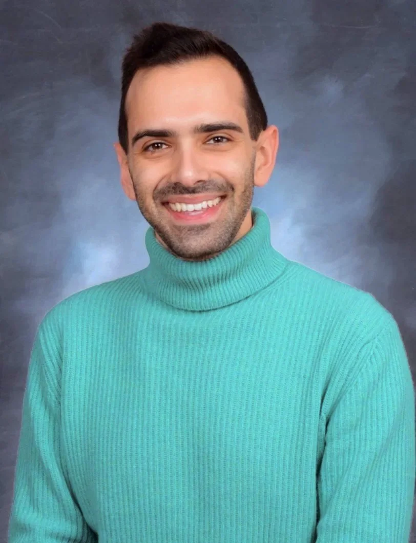 Alex Lewis wearing a green turtleneck sweater on grey background